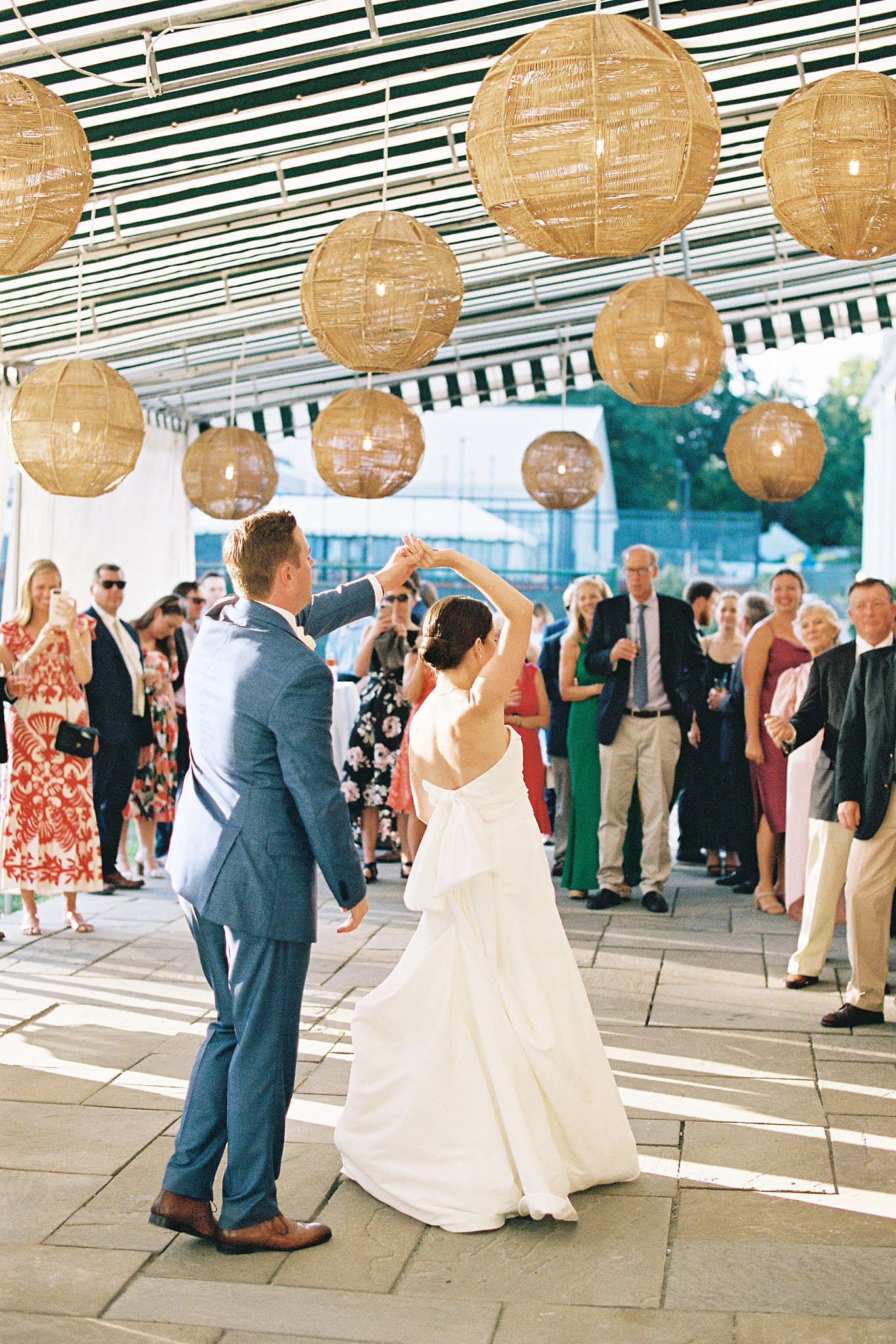 groom spins bride during first dance while guests watch