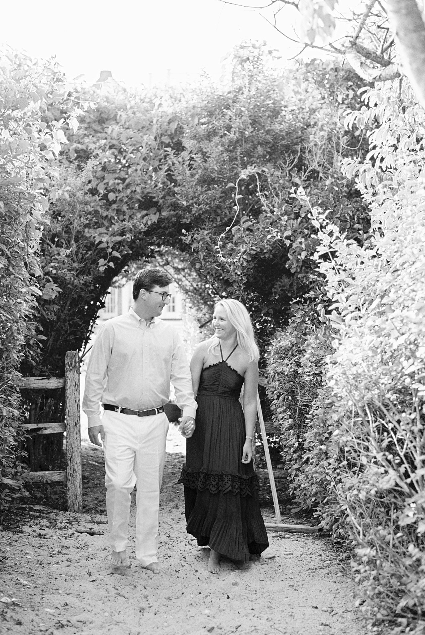 bride to be holds hands with fiance walking through ivy by Lynne Reznick photography 