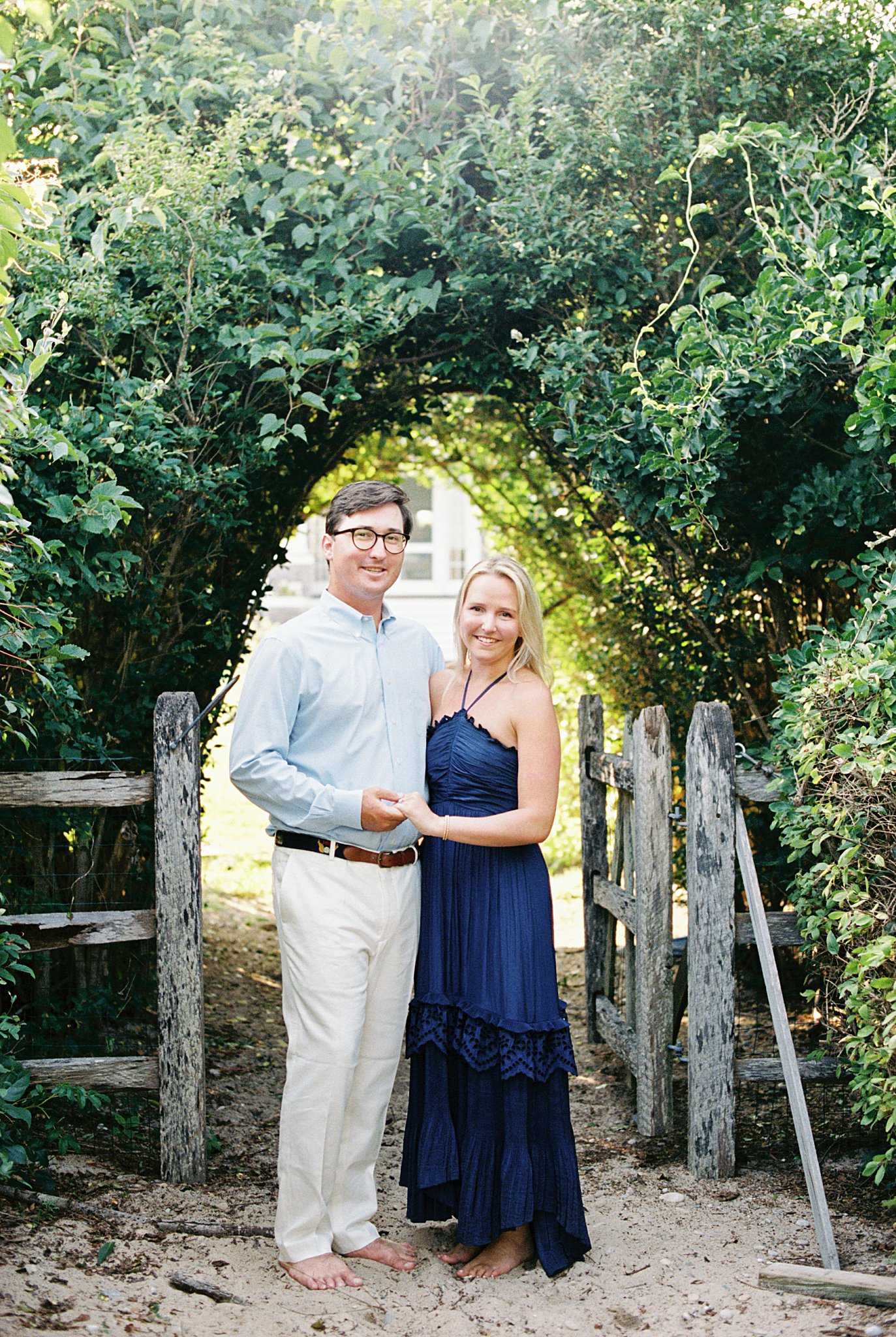 man holds woman's hand with his arm around her at Watch Hill engagement session