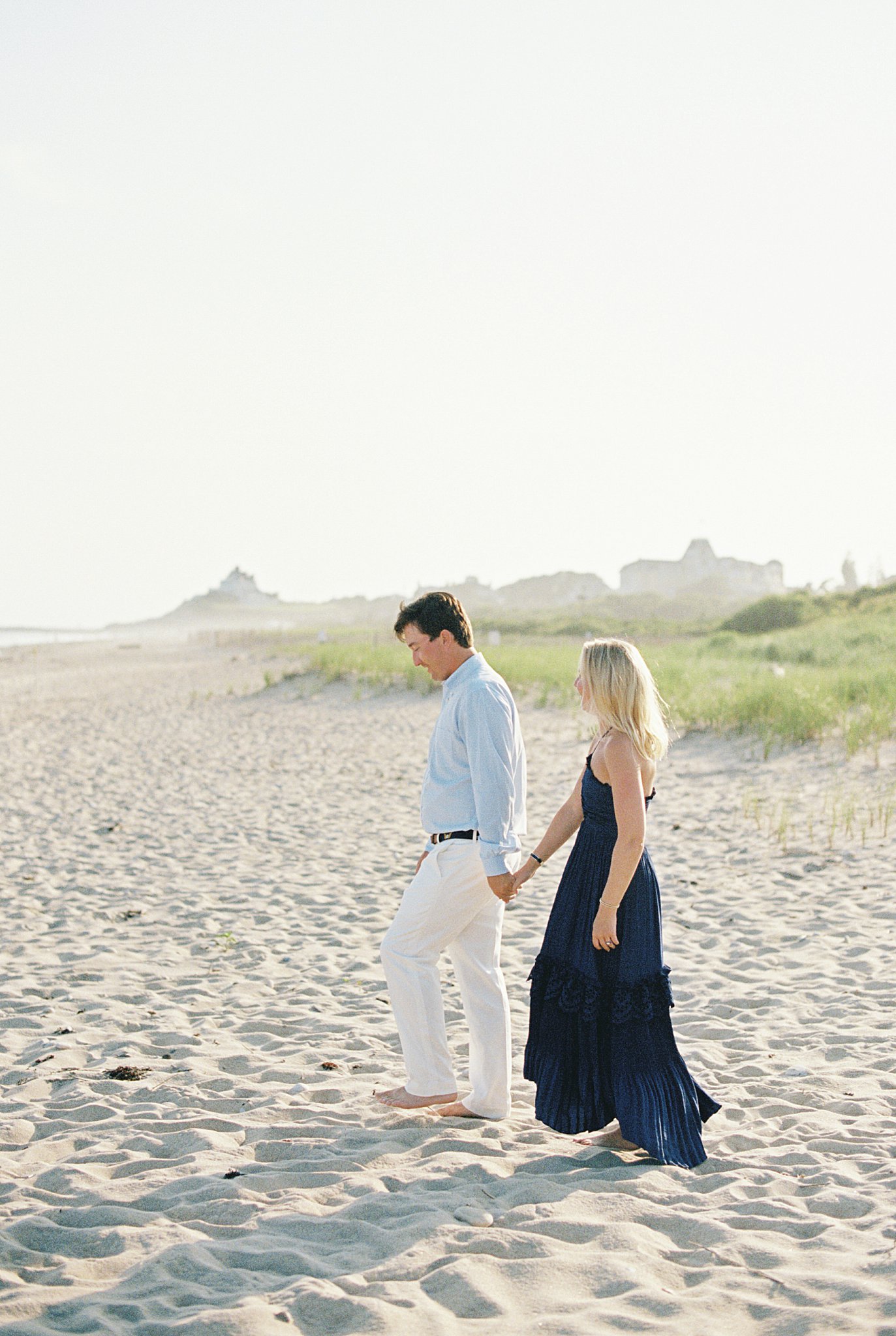 couple walks down to beach during Watch Hill engagement session