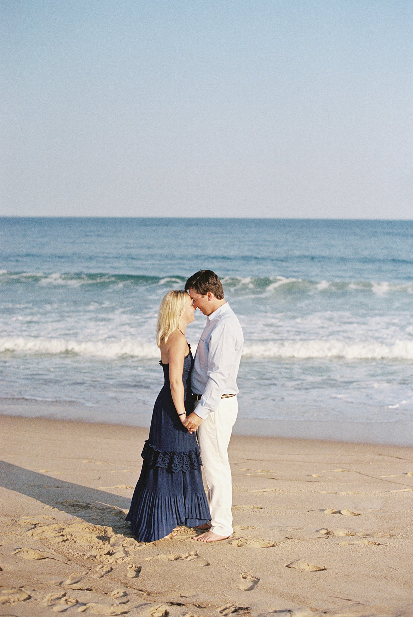 couple stands with foreheads together on shore at Watch Hill engagement session