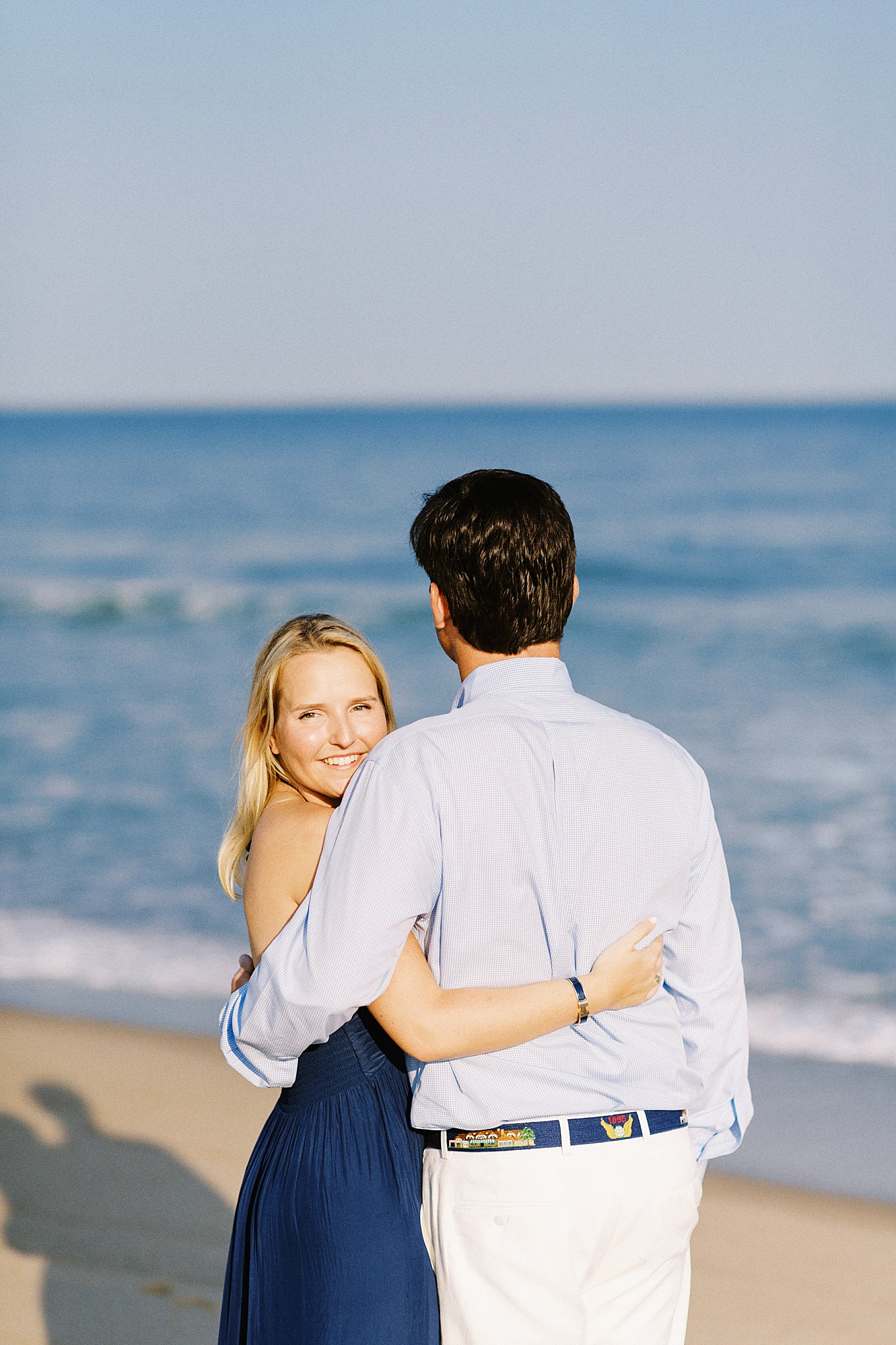 woman looks back over her shoulder as she stands with fiance by Lynne Reznick photography 