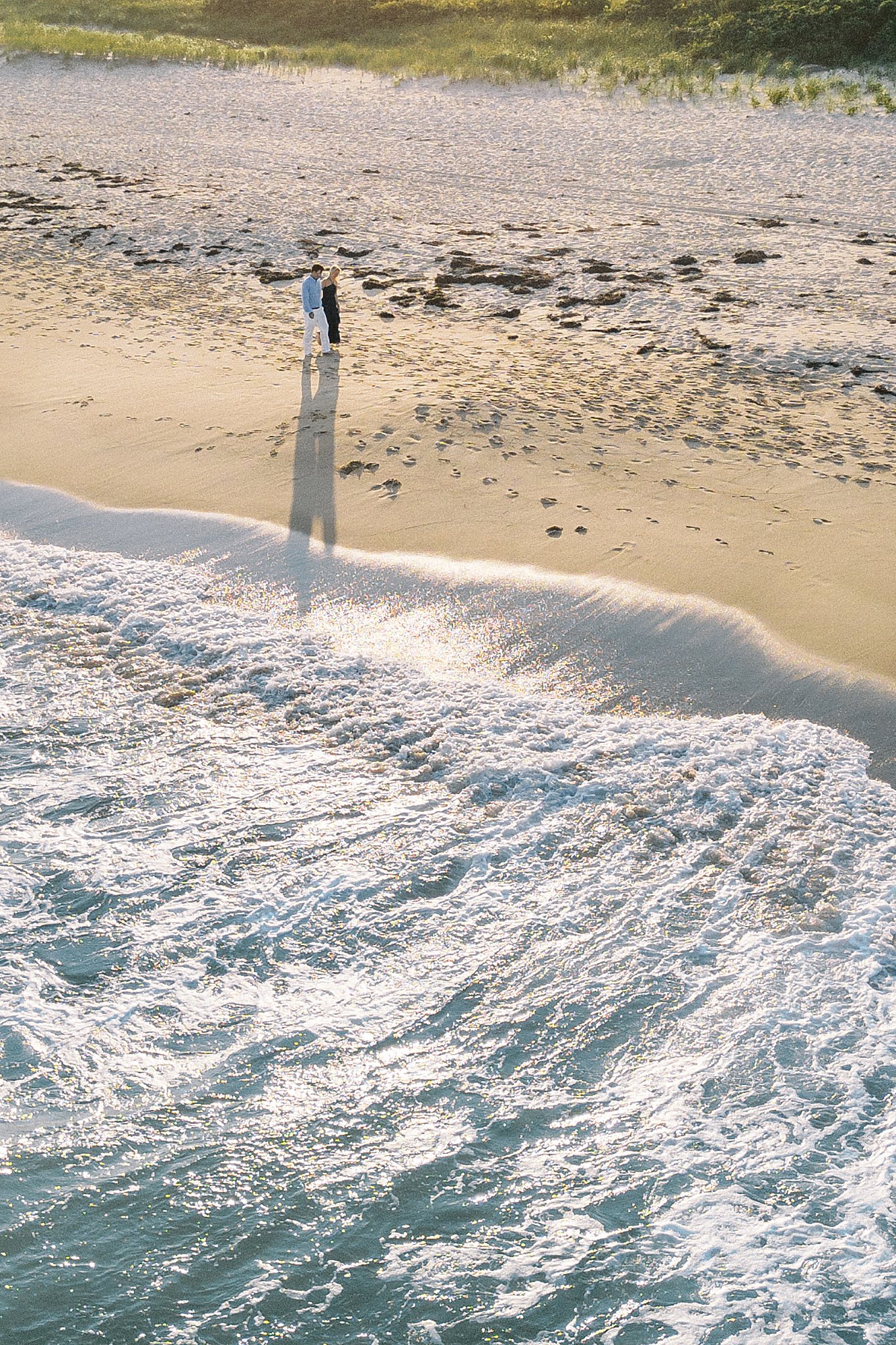 man and woman walk along beach as waves come in by Lynne Reznick photography 