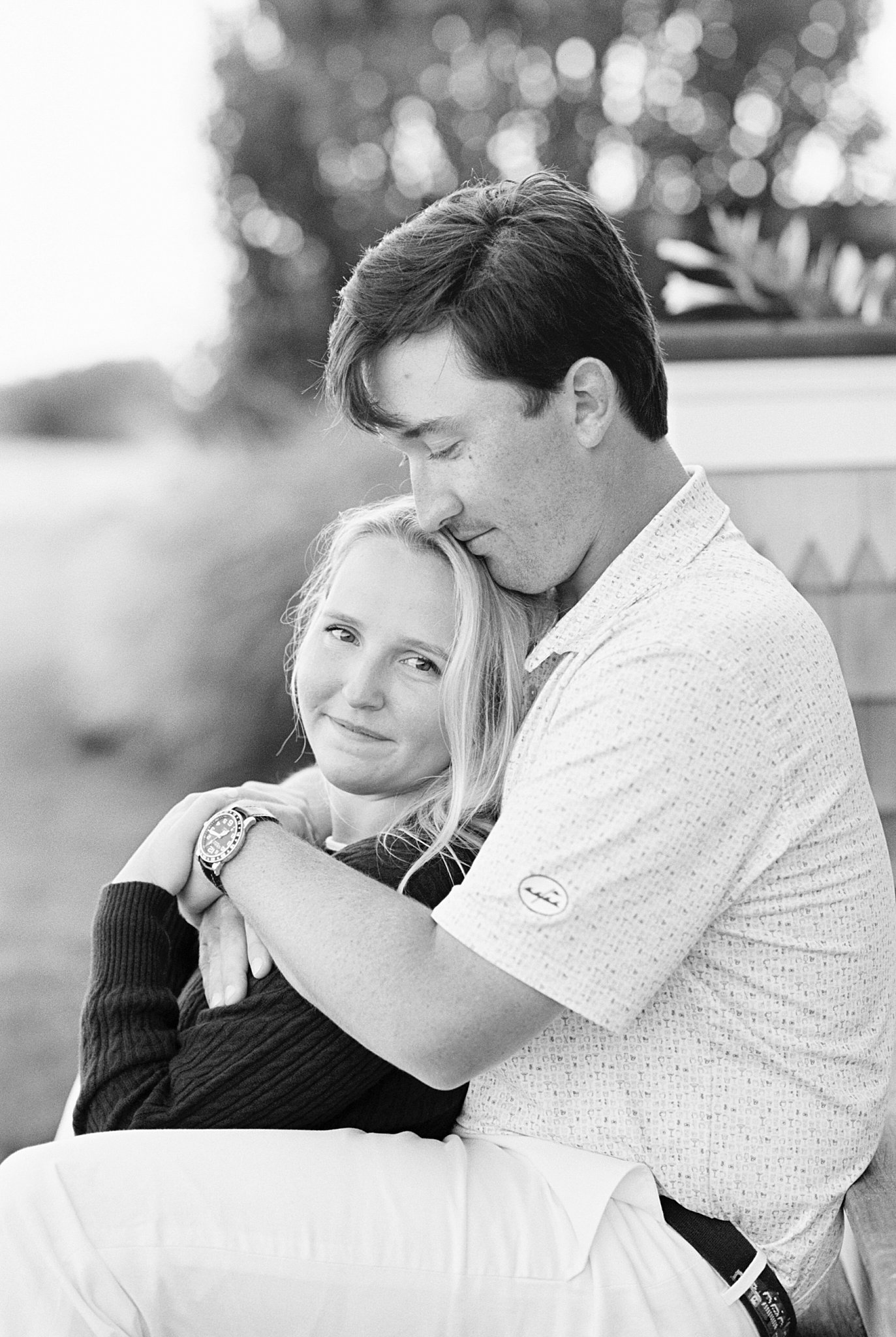 bride to be leans back on fiance by New England wedding photographer