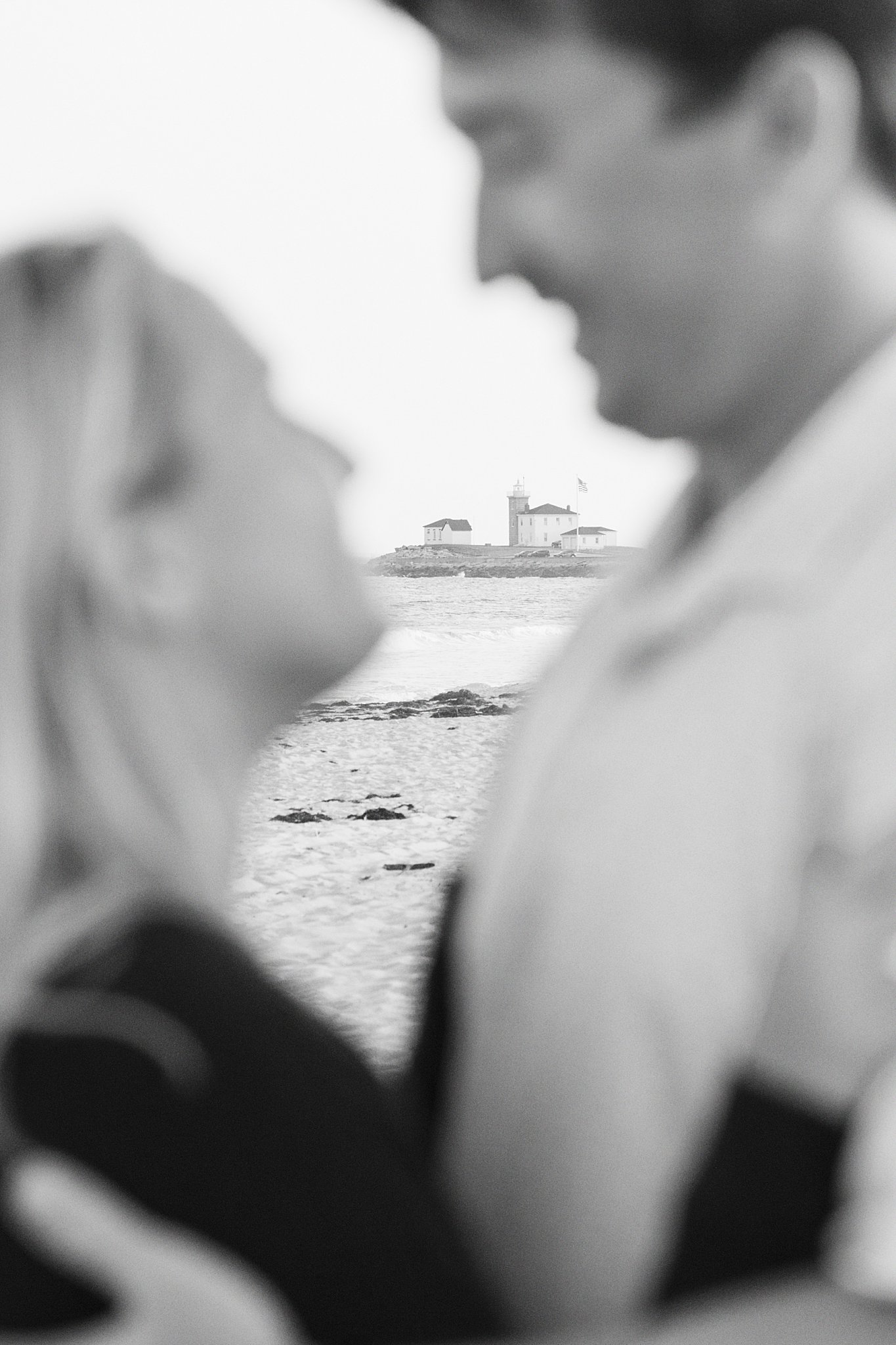 lighthouse peeks out behind couple at Watch Hill engagement session