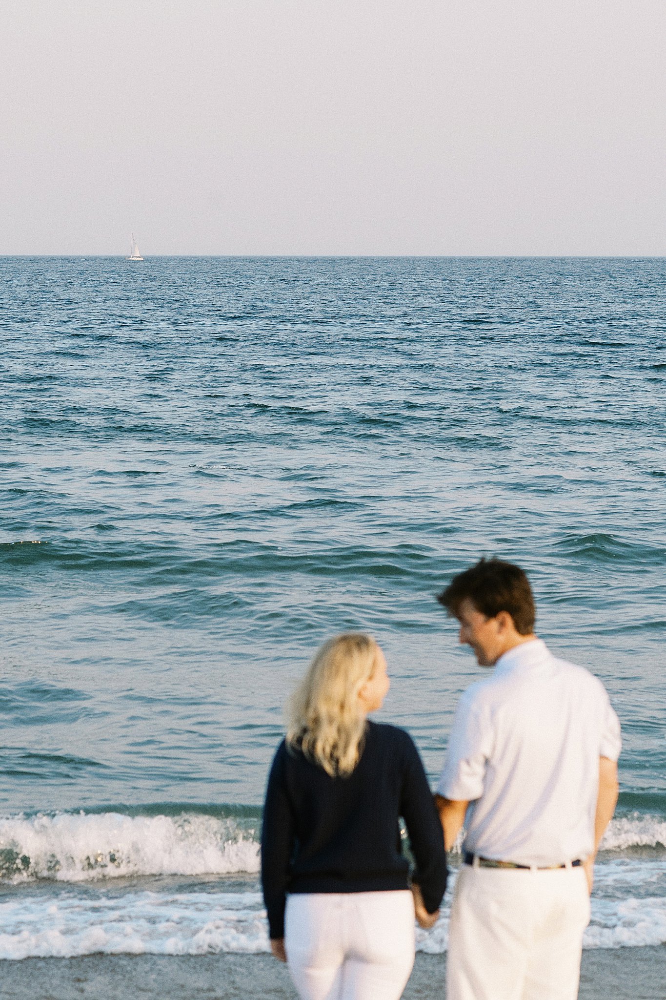 engaged couple holds hands at shore by New England wedding photographer