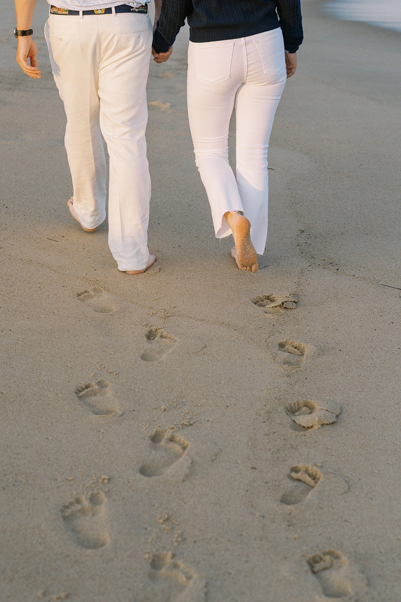 couple leaves footprints in sand by Watch Hill engagement session