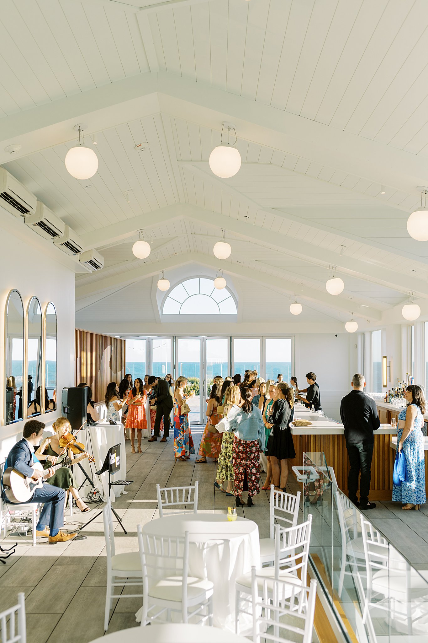 guests enjoy cocktails in large open room with views of cape by Lynne Reznick Photography