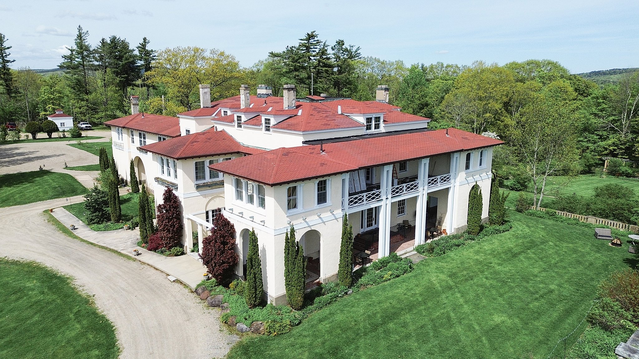 white mansion with red roof on lush lawn by New England wedding photographer