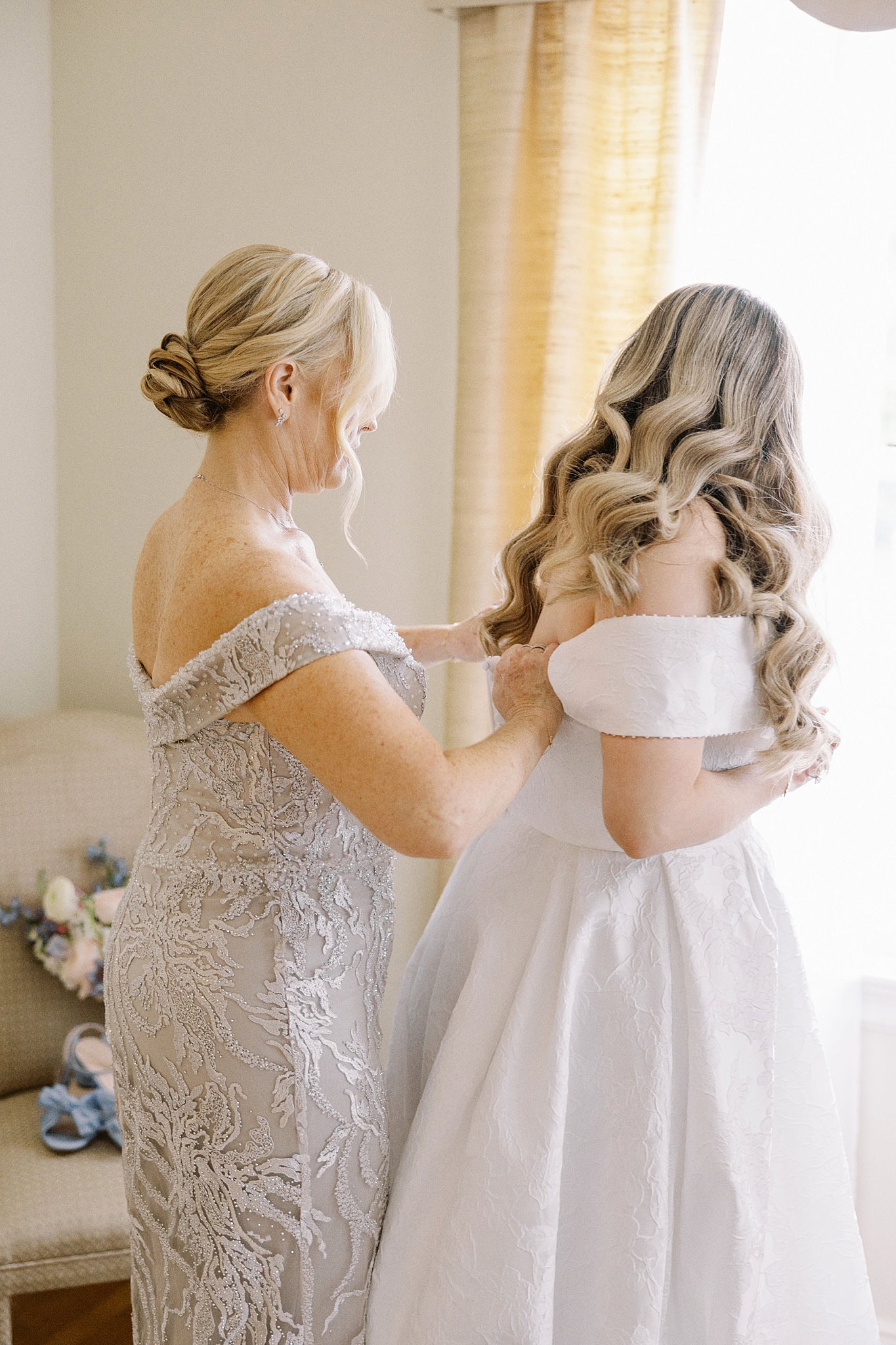 mother helps daughter get into wedding gown by Boston wedding photographer