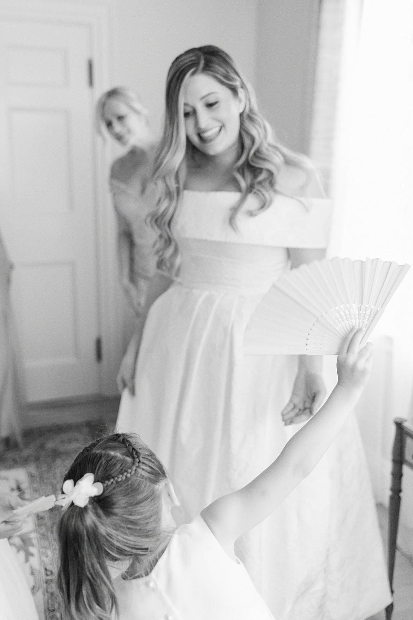 woman smiles at flower girl holding fan by Lynne Reznick Photography