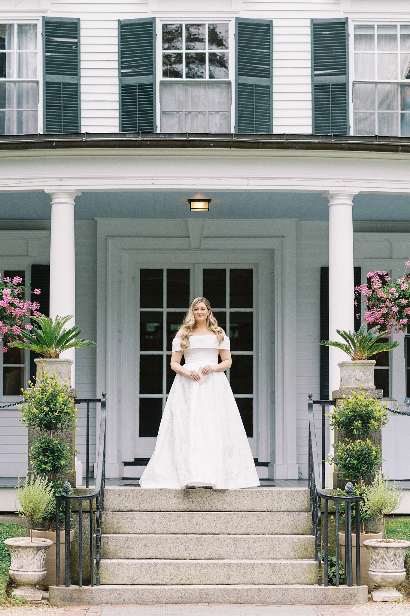 bride stands in front of estate by Lynne Reznick Photography