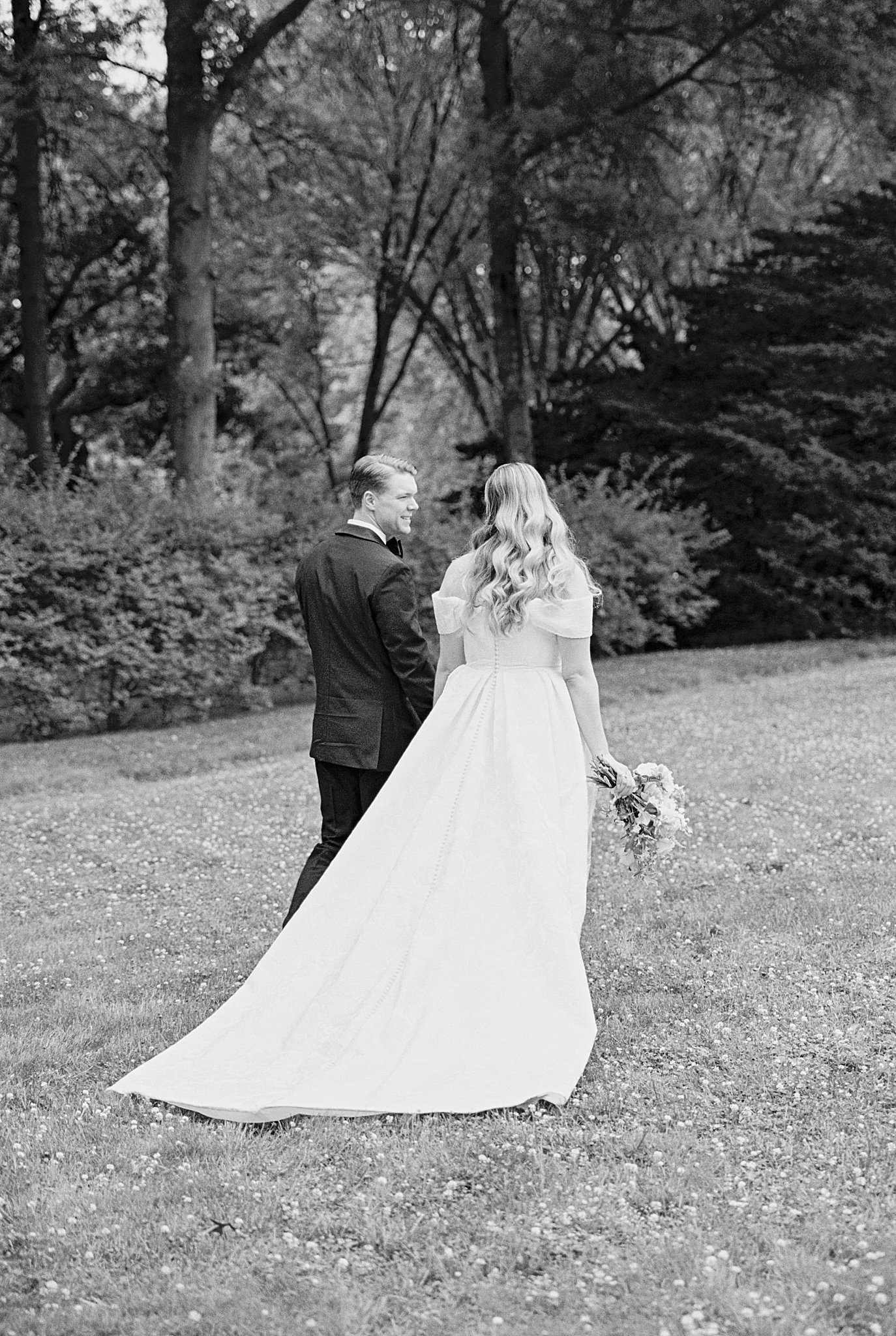 man and woman walk together across lawn by Boston wedding photographer