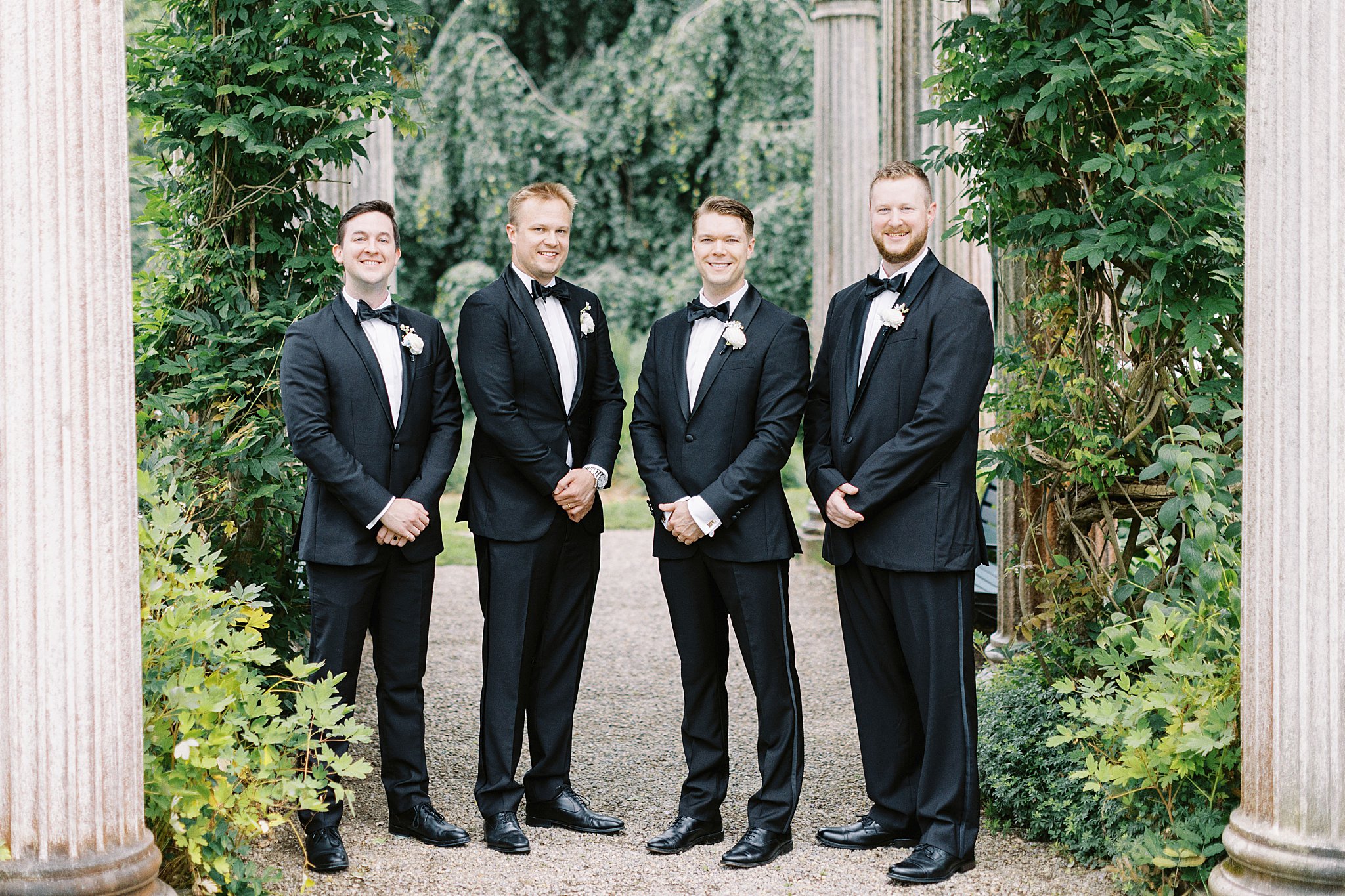 groomsmen stand together with hands clasped in front by Boston wedding photographer