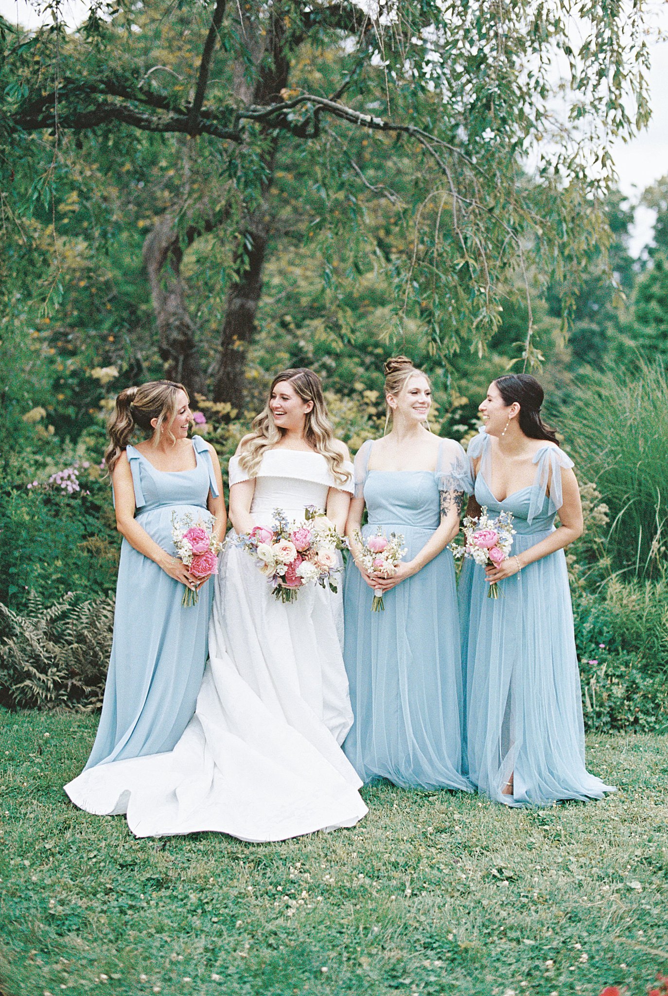 bridesmaids look at each other smiling at Glen Magna Farms