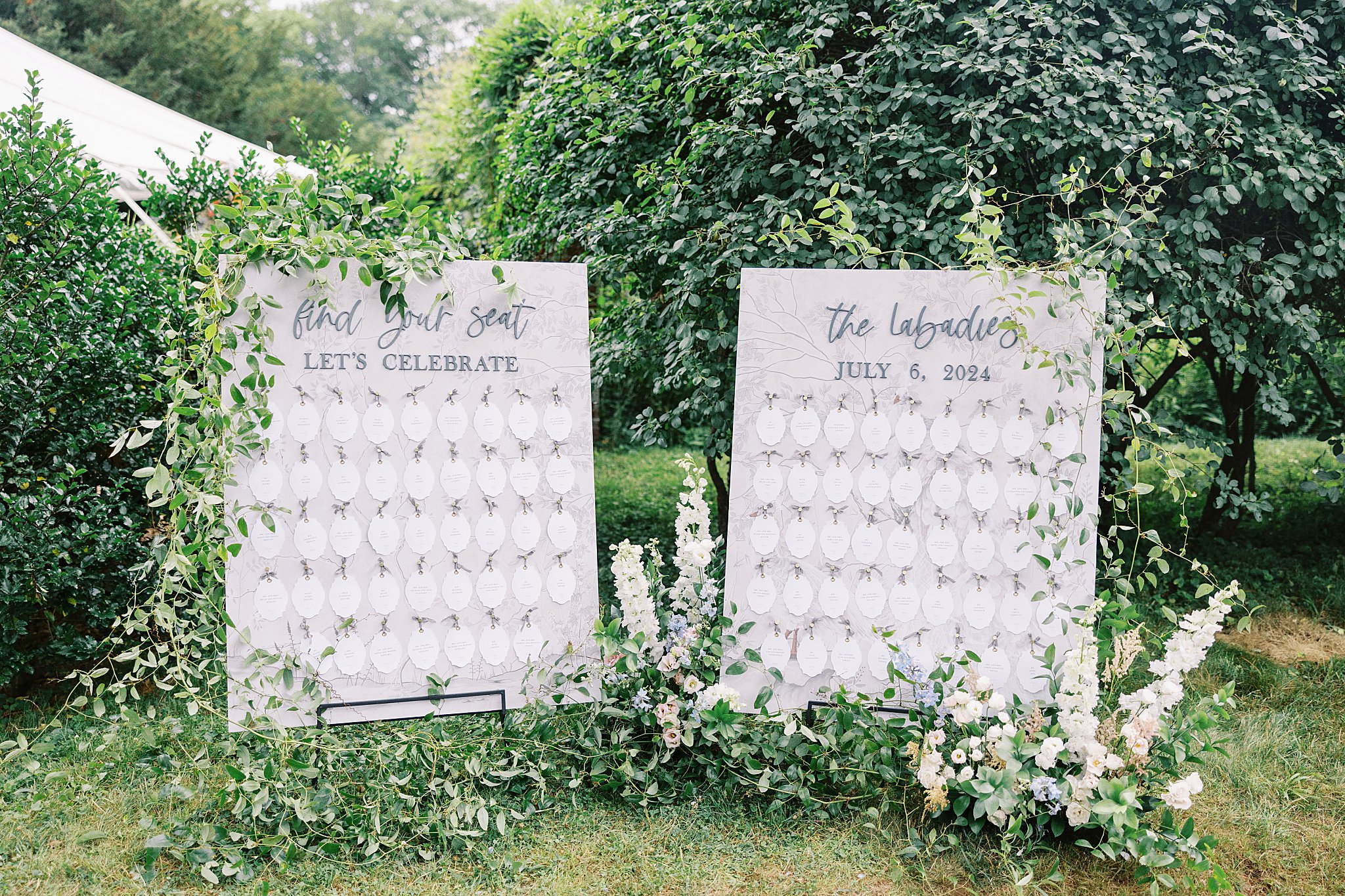 place cards are displayed on boards with greenery by Boston wedding photographer