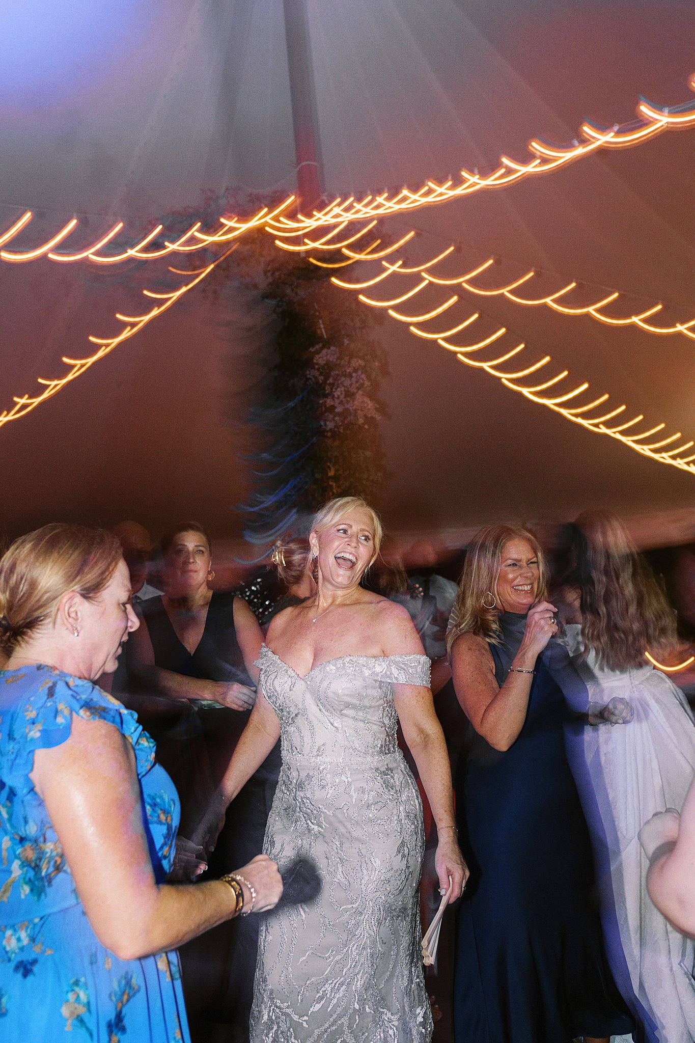 mother of the bride smiles as she dances by Boston wedding photographer