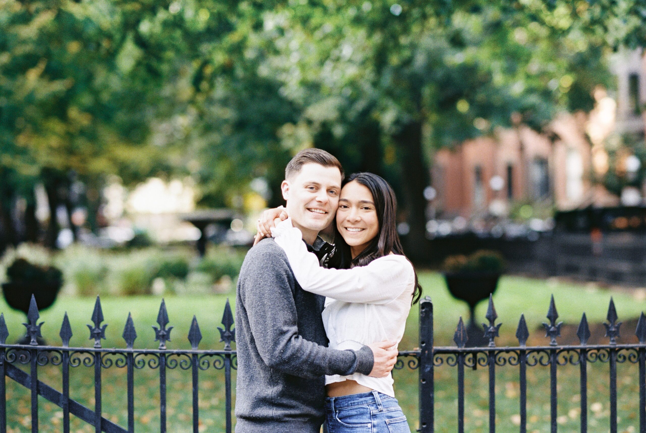 Engaged couple hugs and smiles for the camera in the South End of Boston during their Fall engagement session