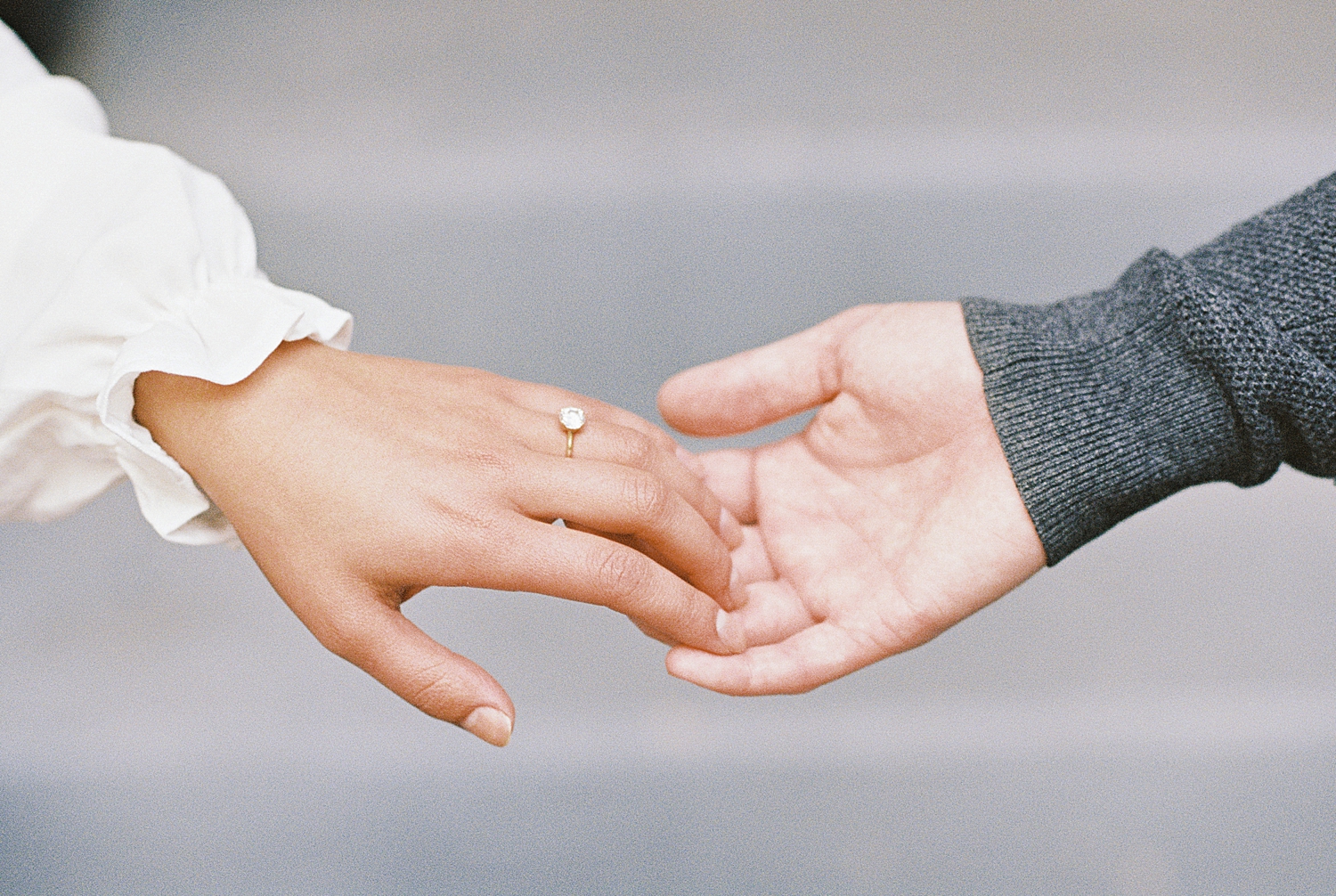 two hands holding fingers with diamond ring by Lynne Reznick Photography