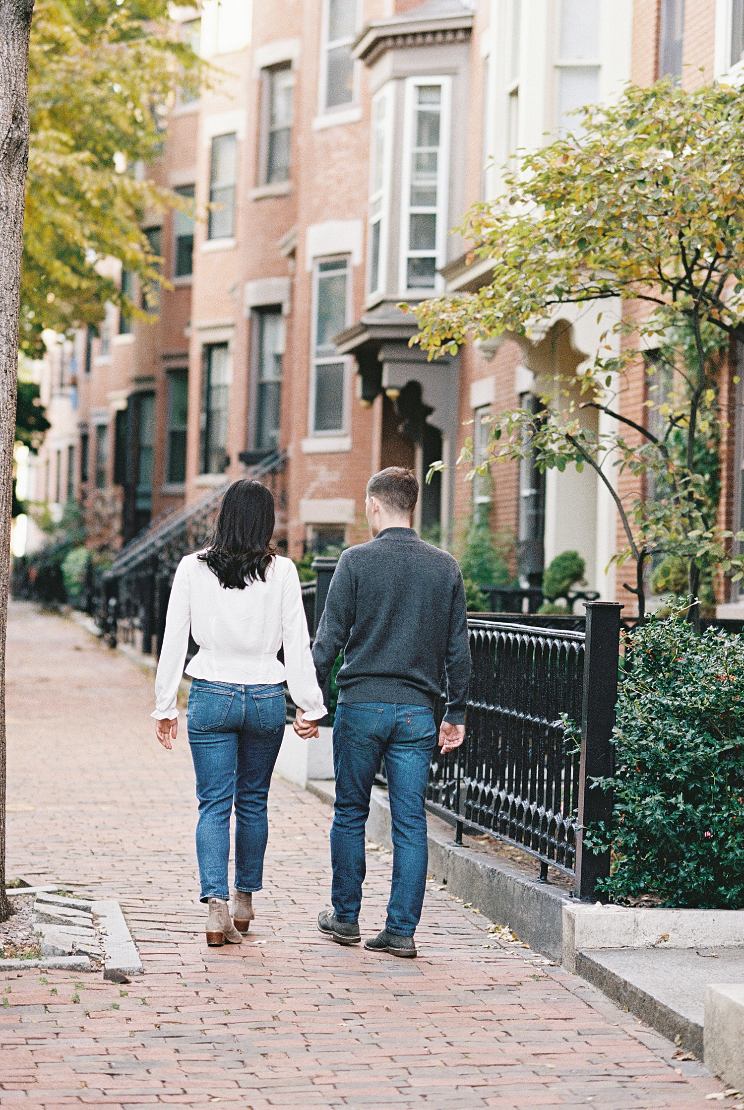 engaged couple walk down sideway by Fan Pier Park Engagement Session