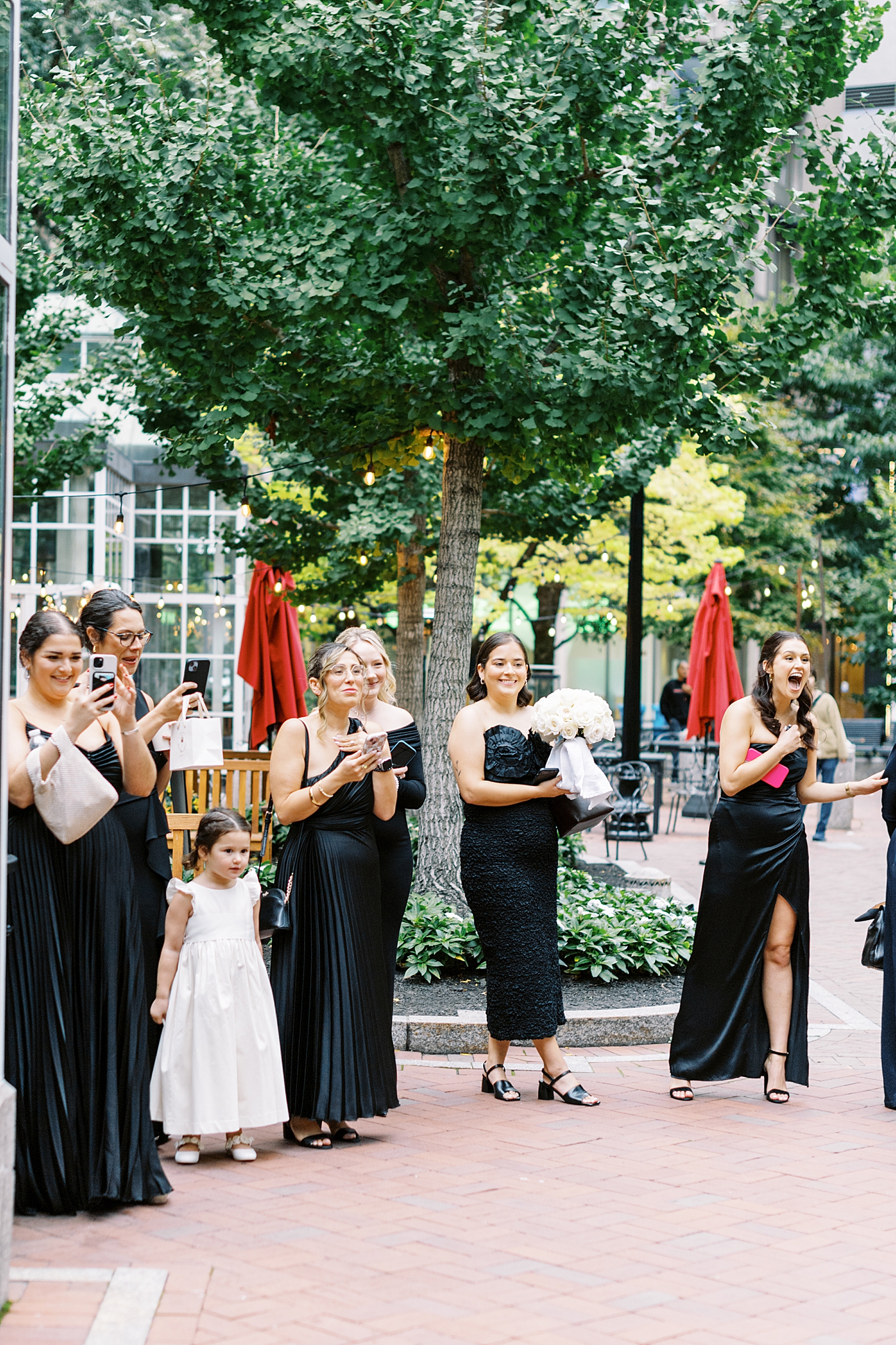 women in black attire watch a first look on the street by Boston Wedding Photographer 