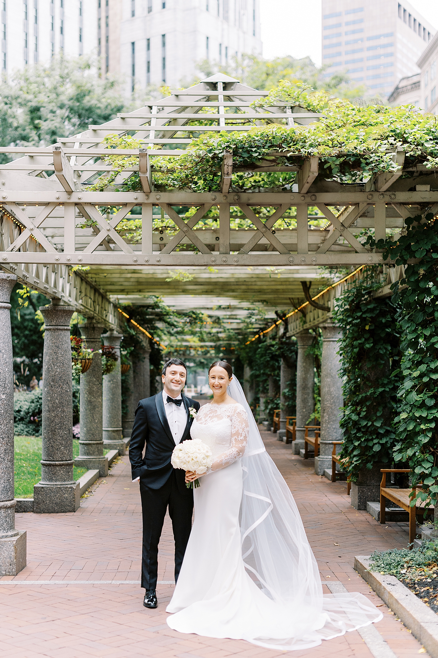 man and woman stand under outdoor arch by Langham Hotel