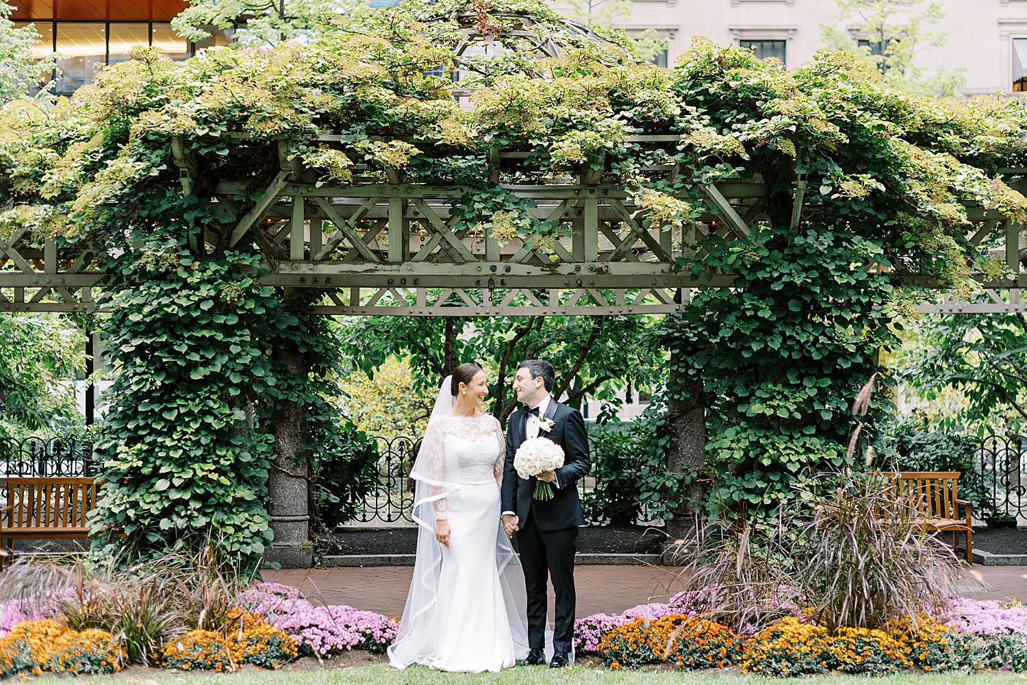 brunette couple stand under large arch of greenery by Lynne Reznick Photography