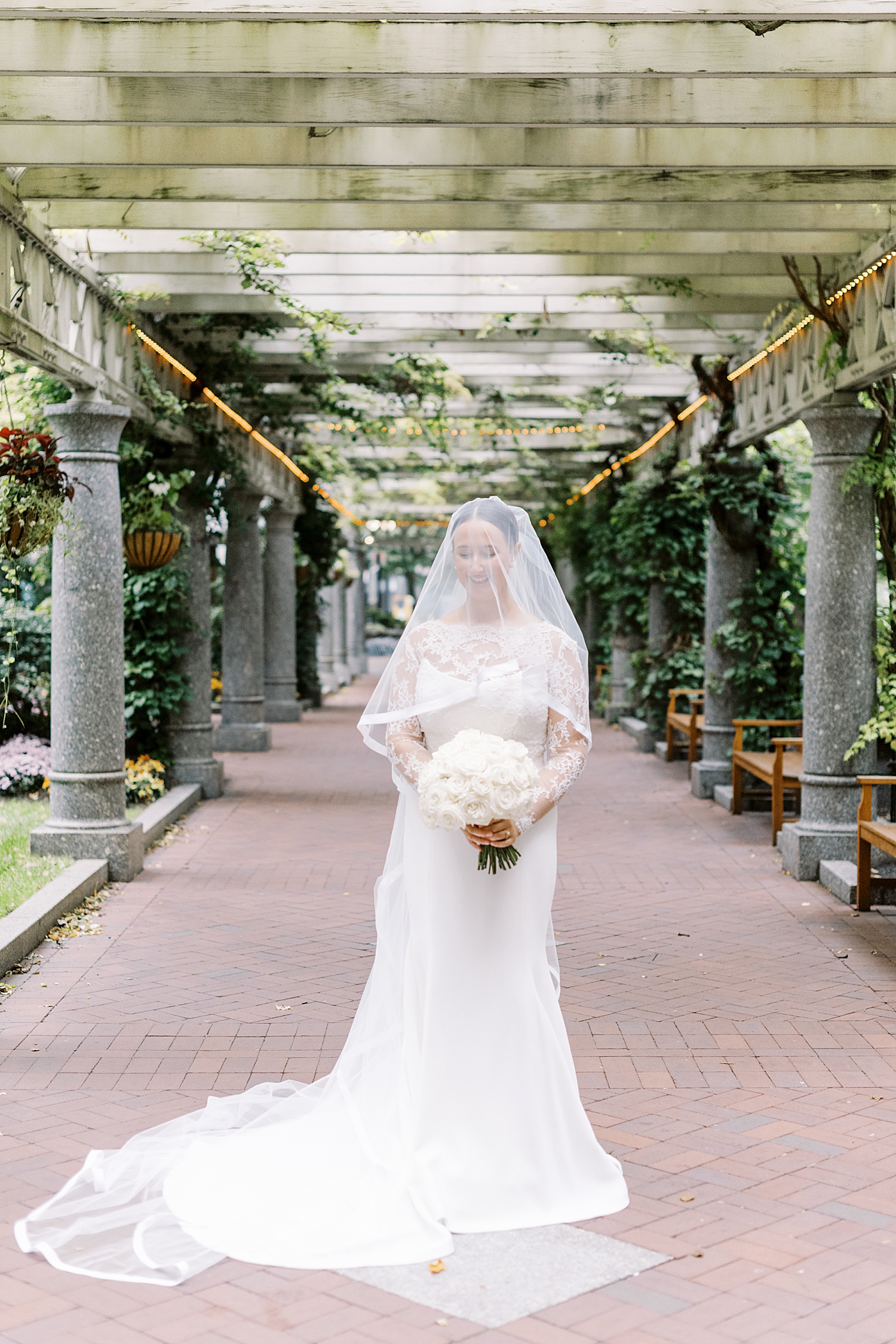 bride stands on brick pathway by Lynne Reznick Photography