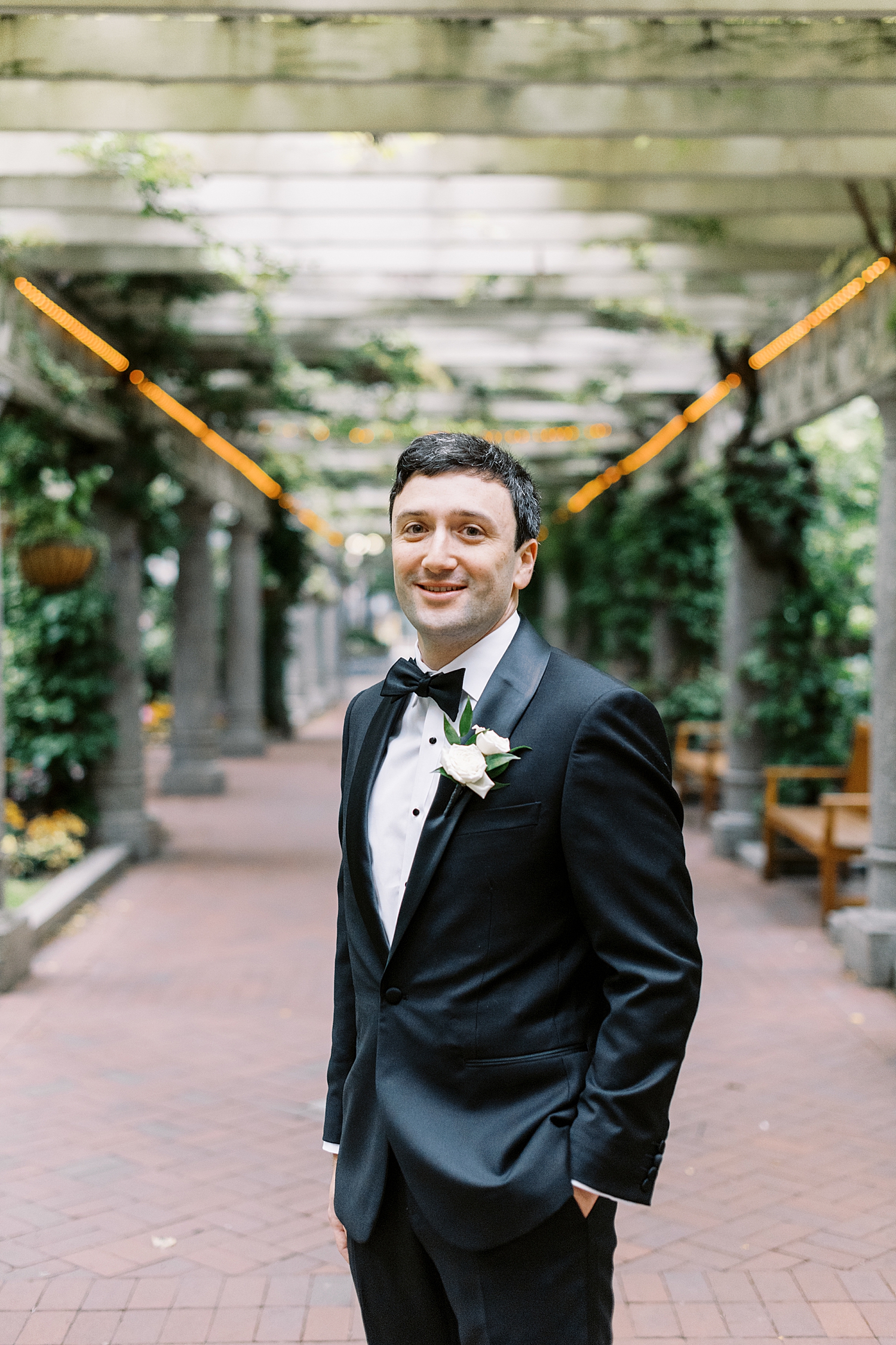 groom stands under garden walkway by Lynne Reznick Photography