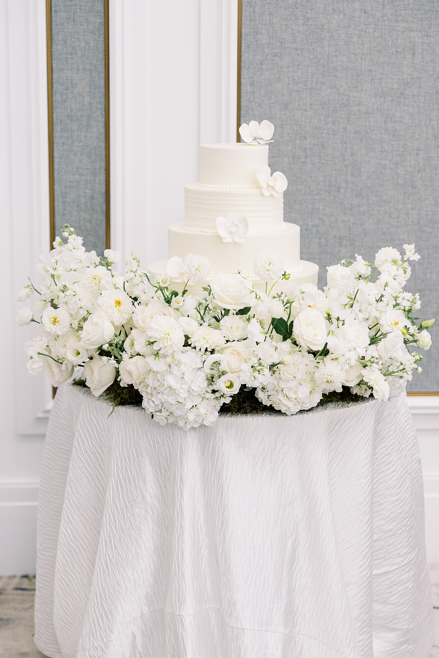 three tiered white cake on table by Lynne Reznick Photography