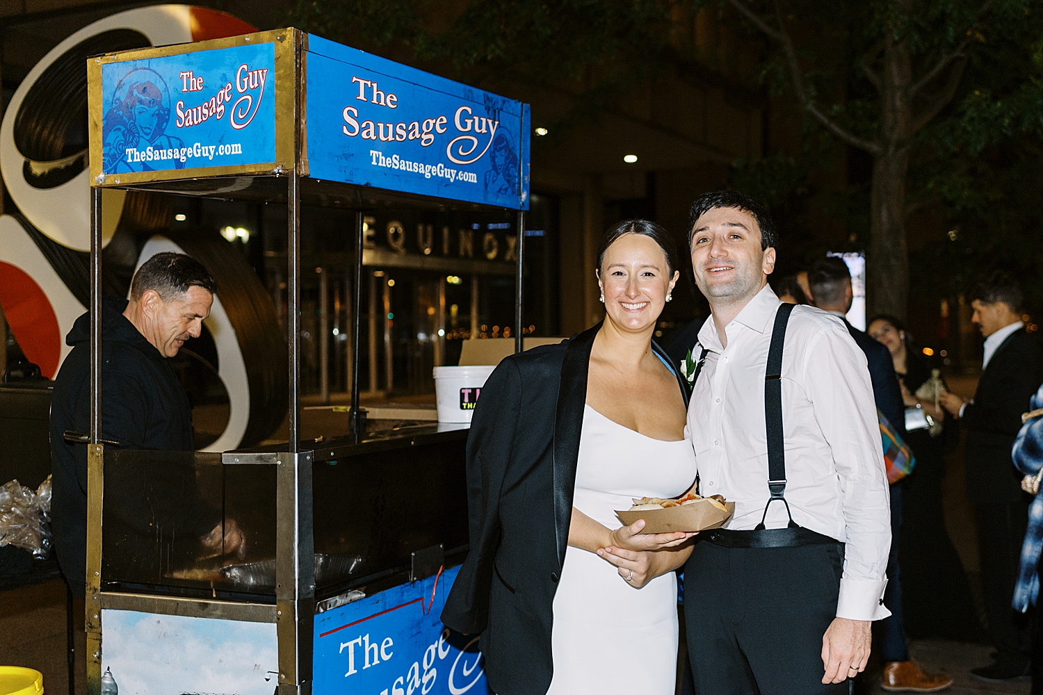 newlyweds eat sausage from a food cart by Boston Wedding Photographer 