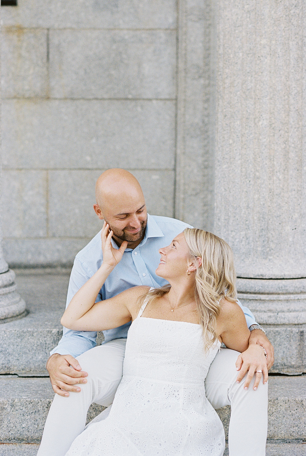 Woman holds man's chin and smile at each other during their Charlestown Engagement Session 