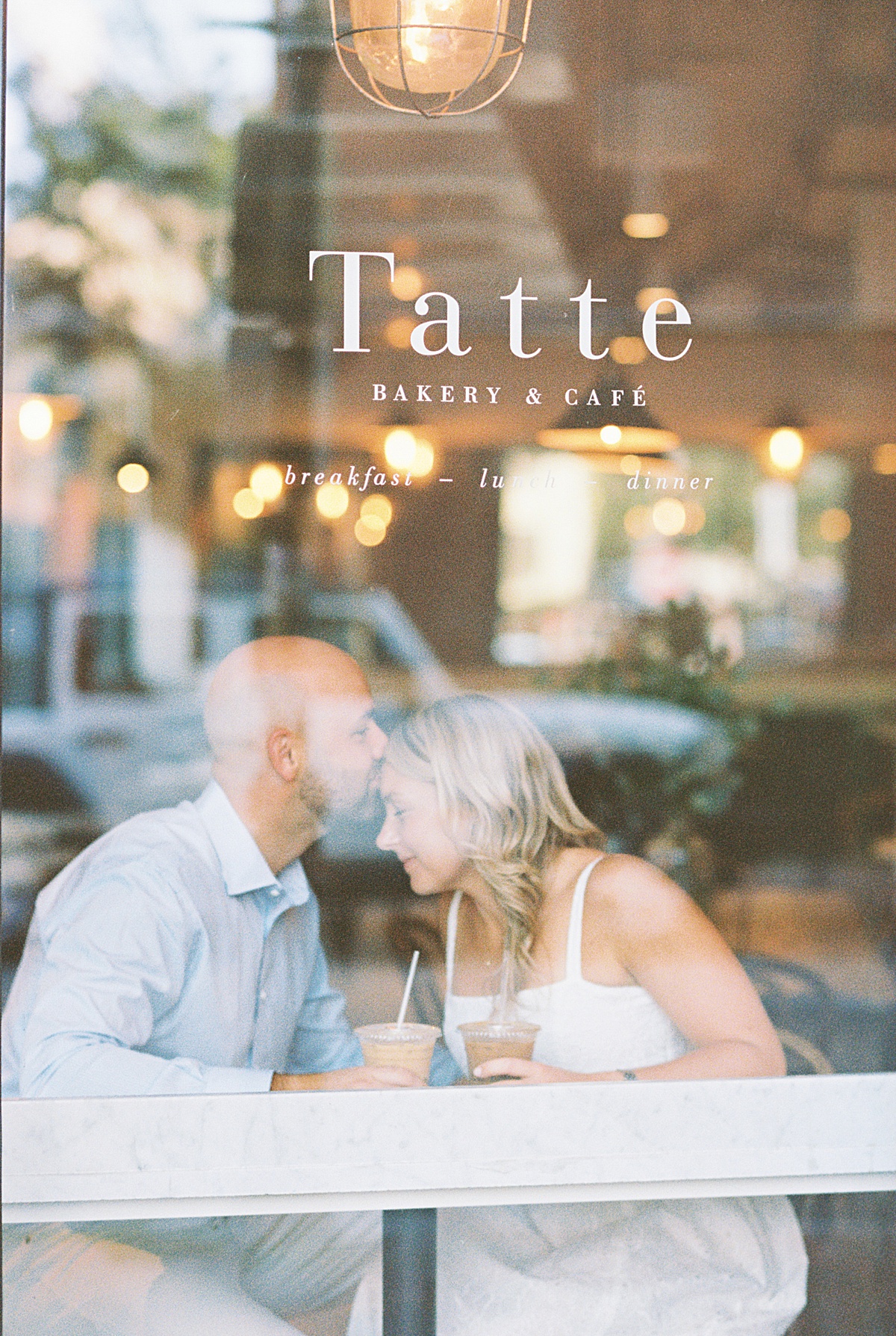 Man kisses woman on the forehead in a coffee shop during their Boston Engagement Session 