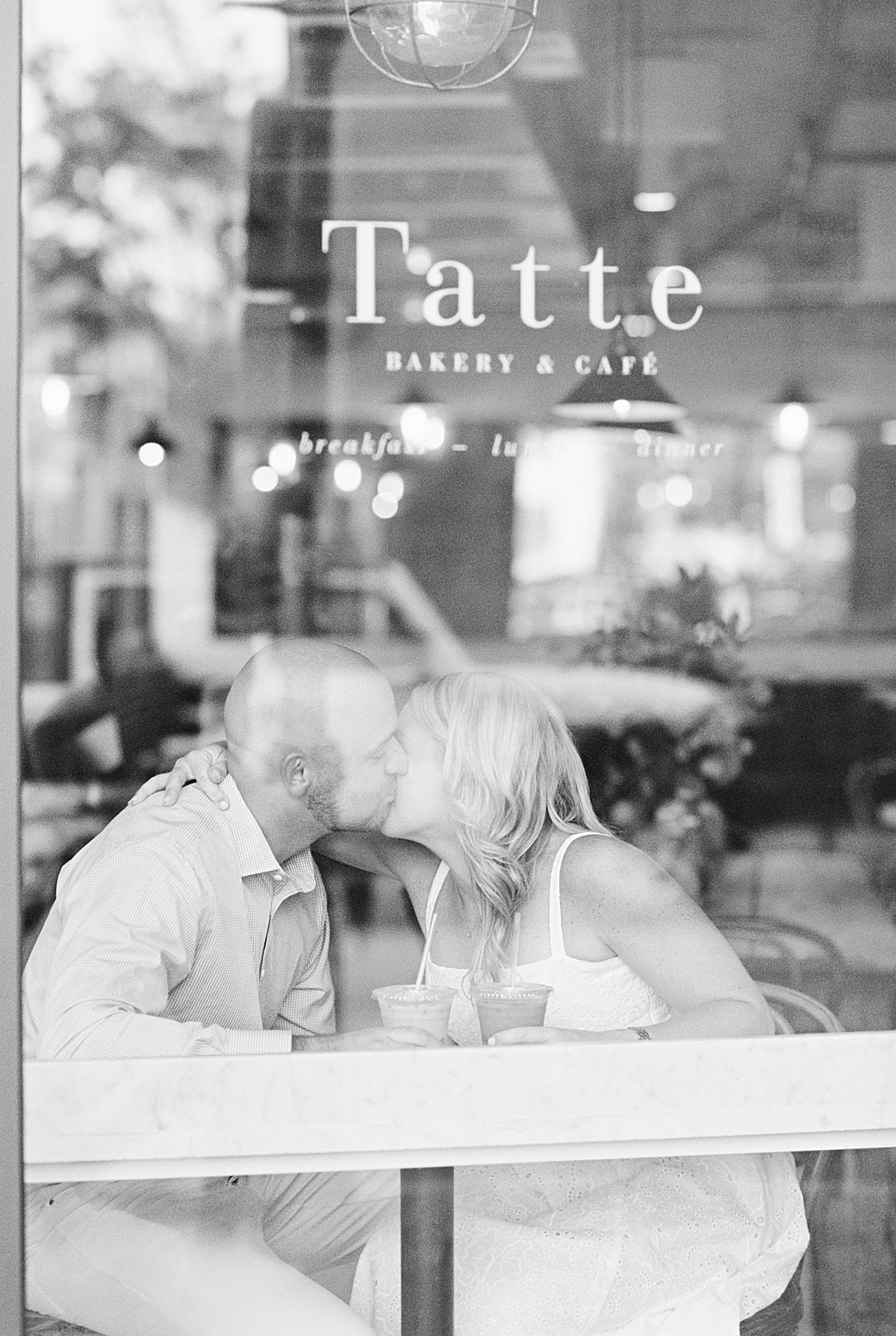 Couple share a kiss in a coffee shop for Boston Wedding Photographer