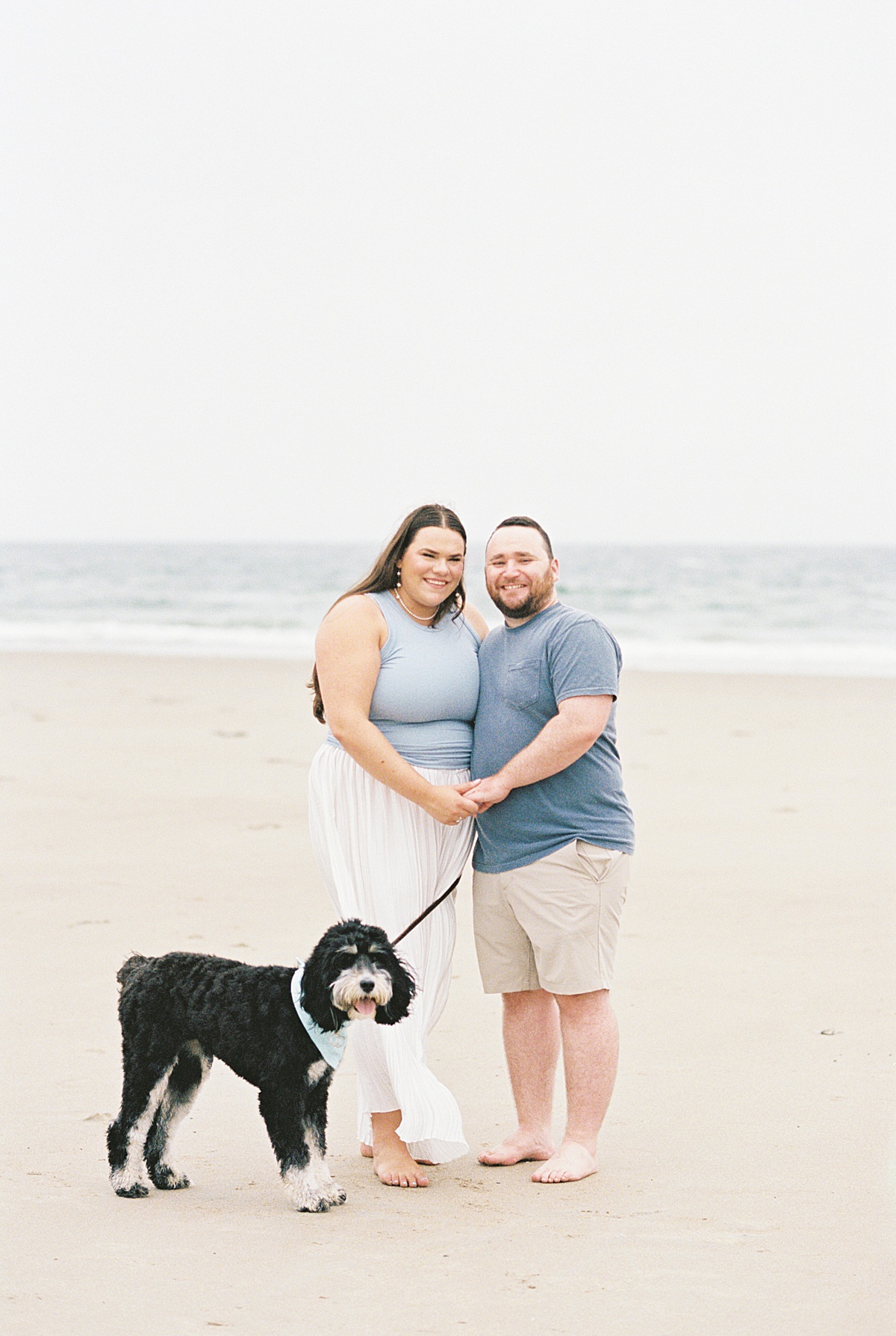 Happy couple share big smiles with their dog on Footbridge Beach 