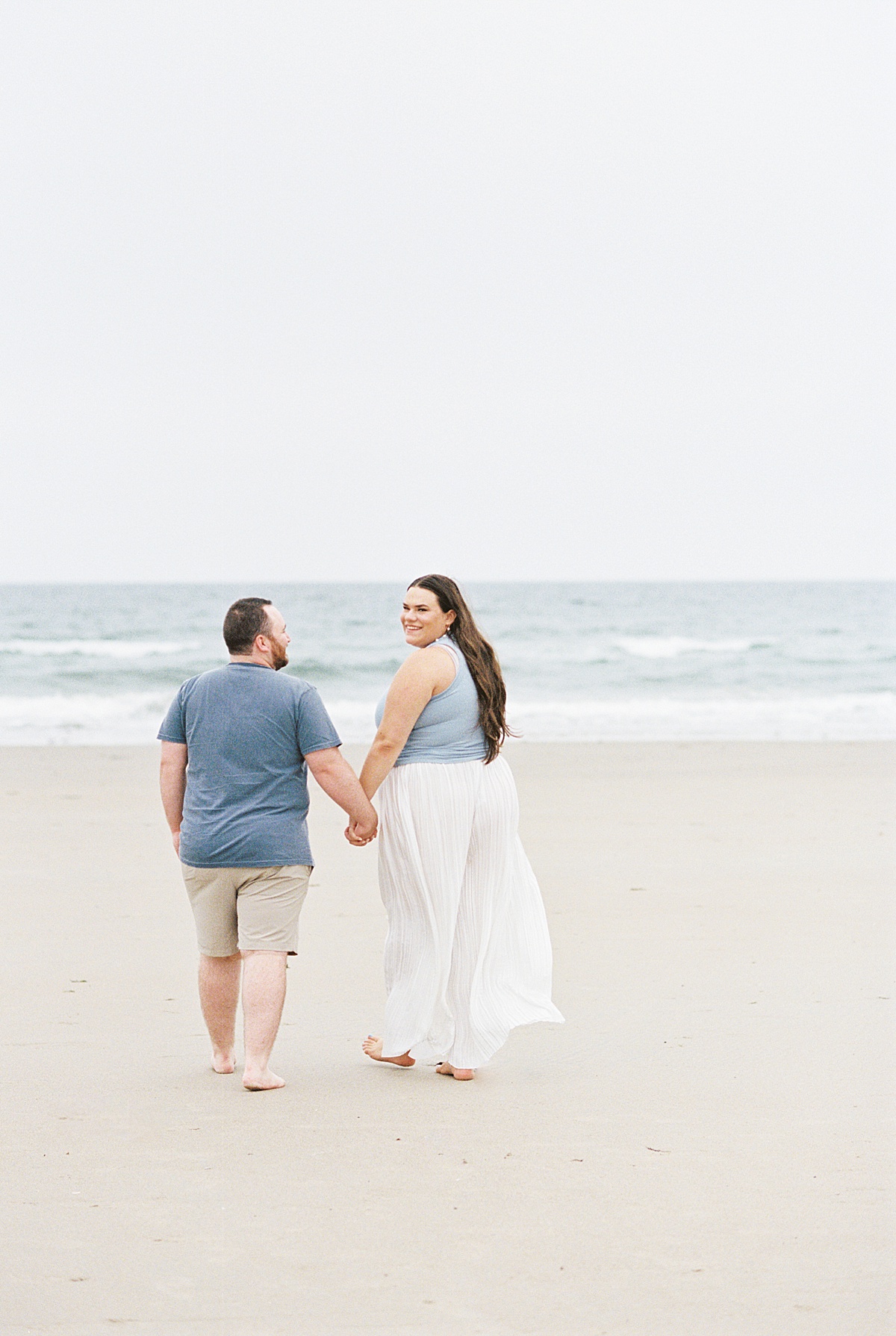 Couple walk hand in hand together on Footbridge Beach 