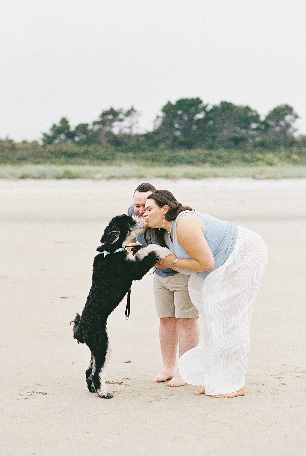 Couple holds their dog close on Footbridge Beach 