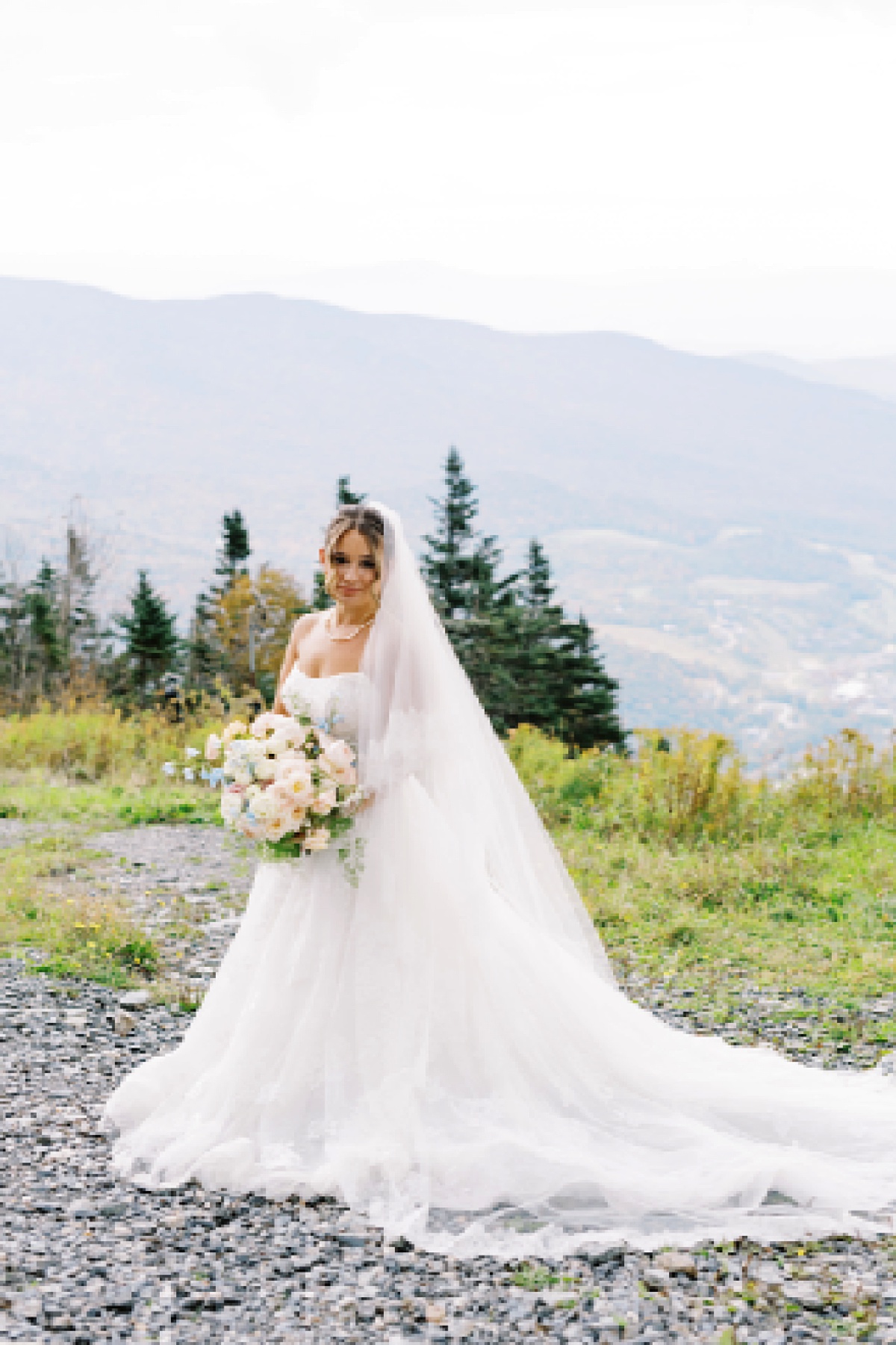 Bride stands on mountain with bridal bouquet at The Lodge at Spruce Peak