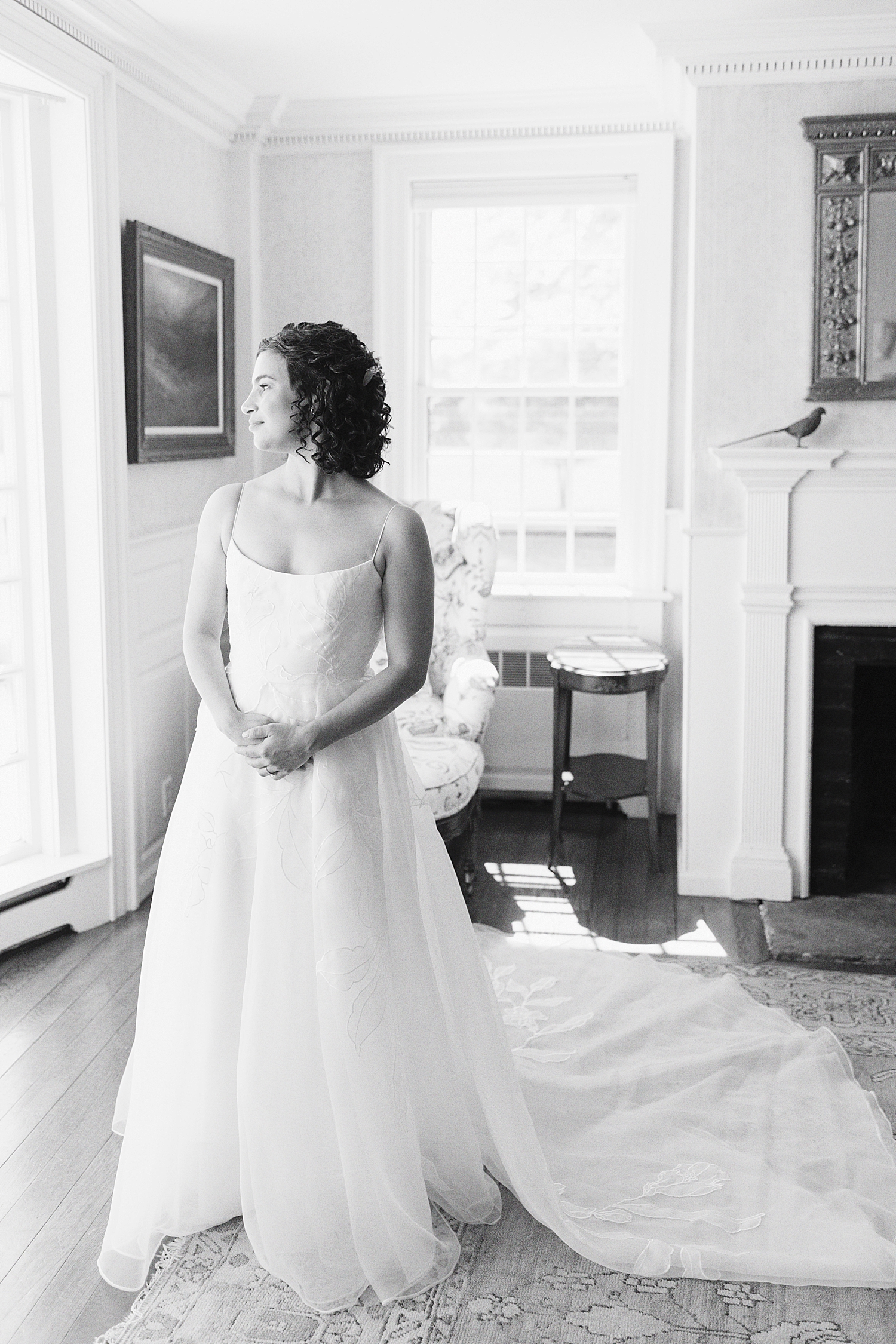 bride stands by window in her gown by Lynne Reznick Photography