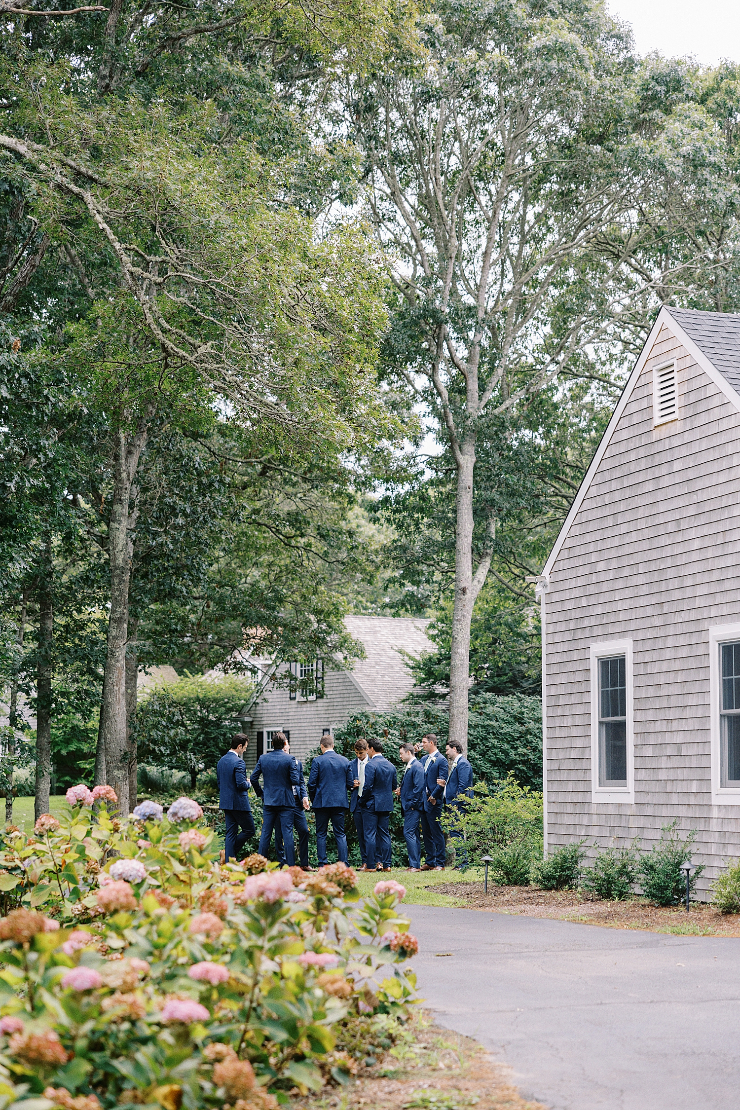 groomsmen in blue mingle outside on lawn at Oyster Harbors Club