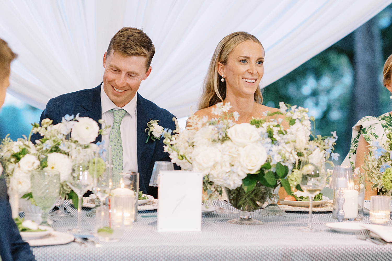 newlyweds enjoy toasts while sitting at table by Lynne Reznick Photography