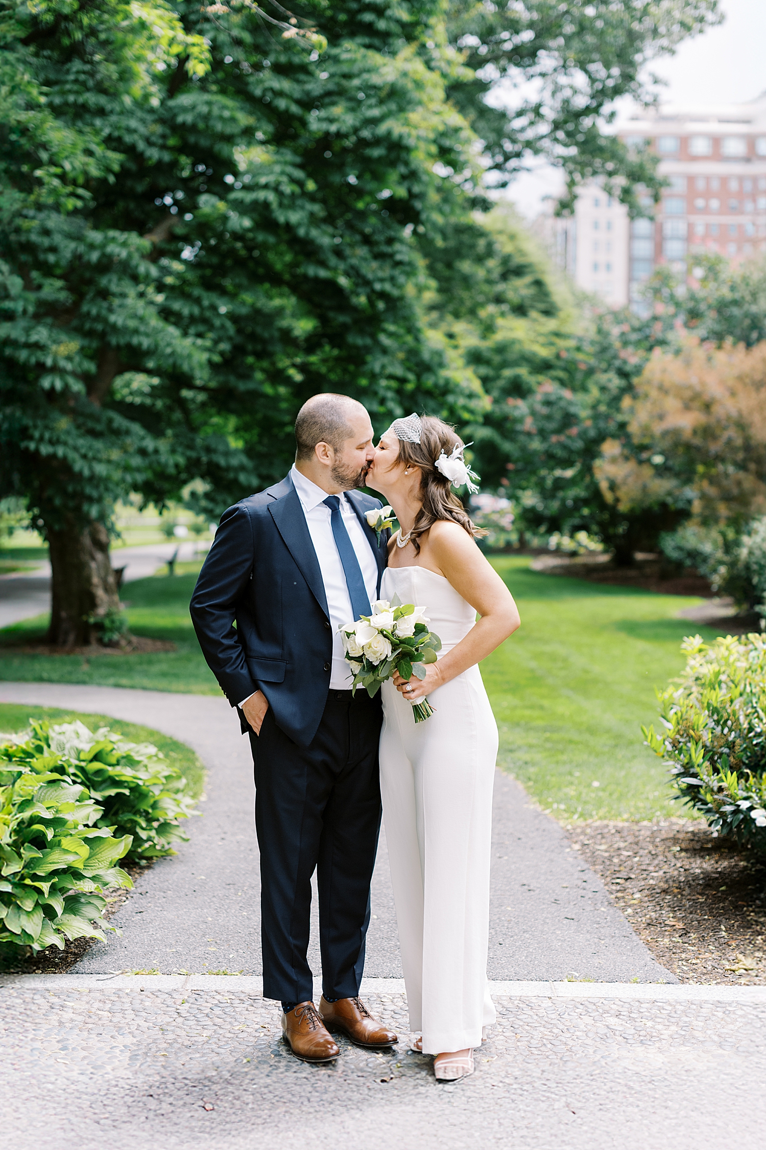 woman with birdcage veil kisses her husband in park by Lynne Reznick Photography