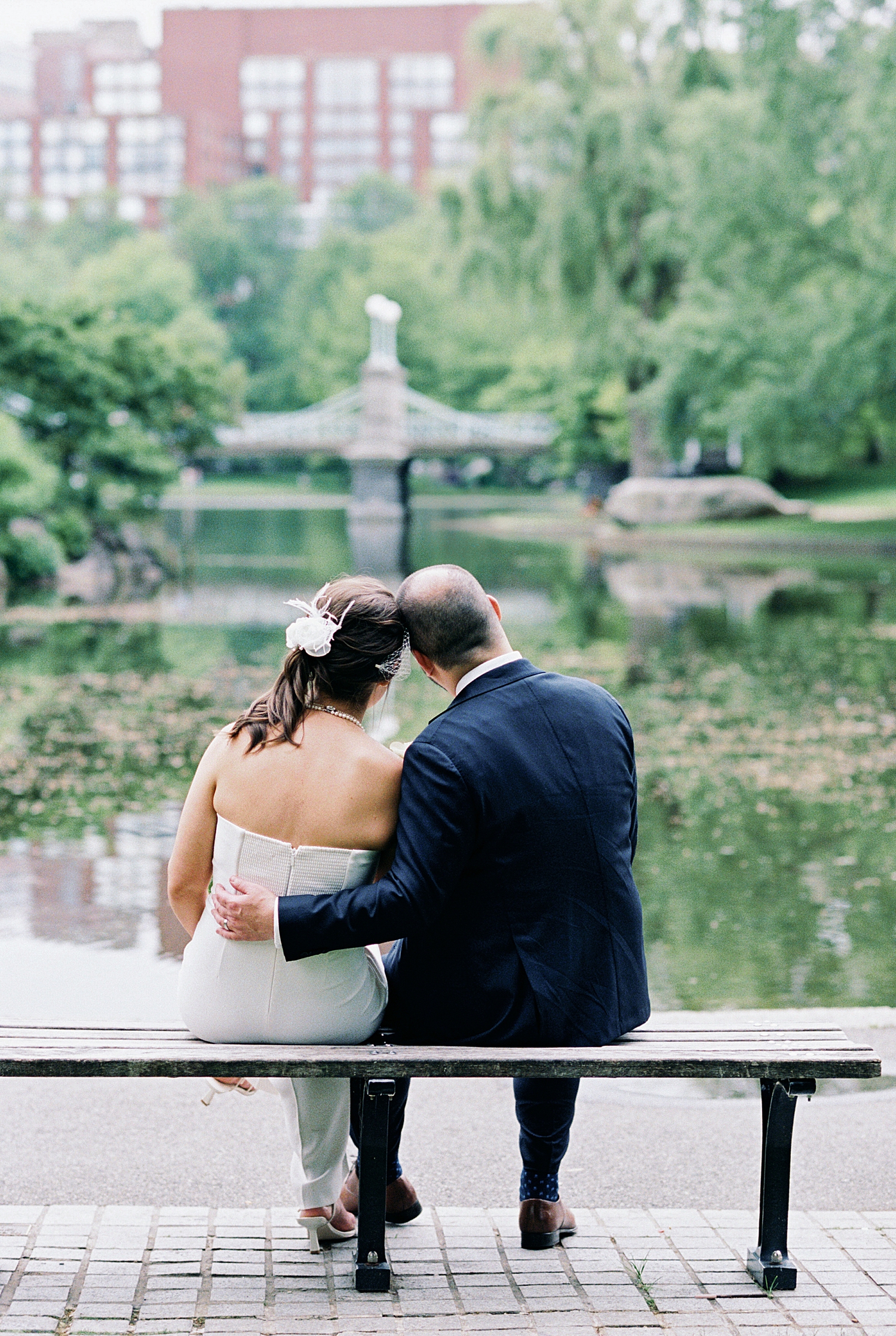 man and wife snuggle on bench looking over pond by New England Wedding Photographer
