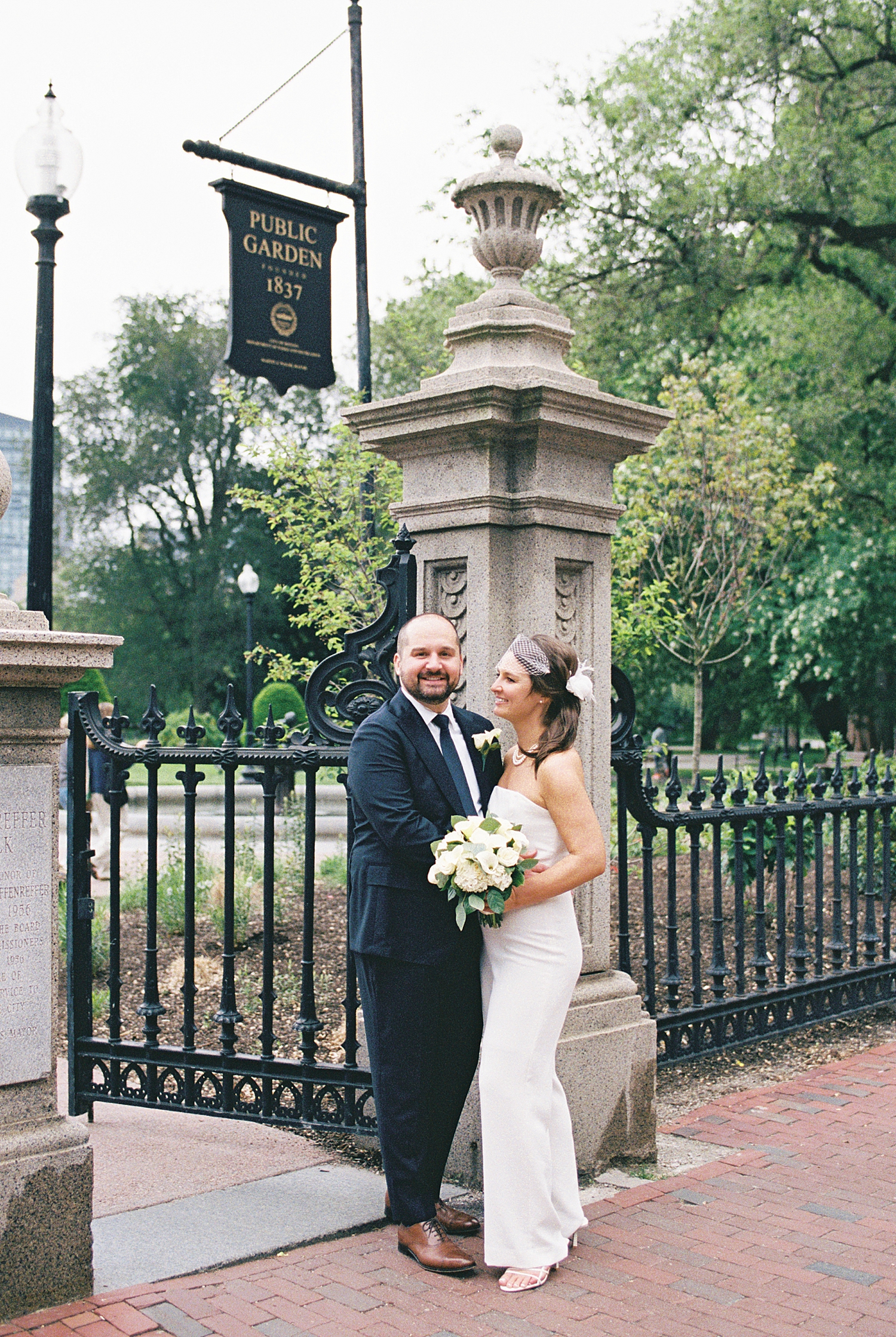 man in suit holds new wife under park sign by Lynne Reznick Photography