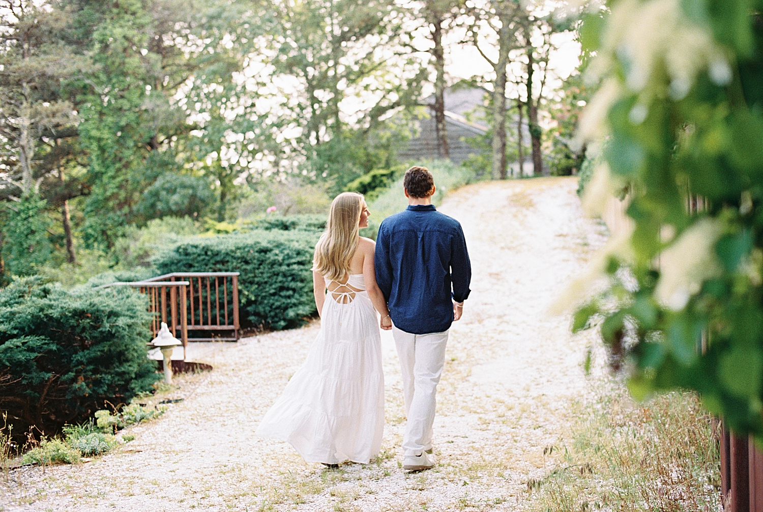 couple walk hand in hand down a pathway by New England wedding photographer