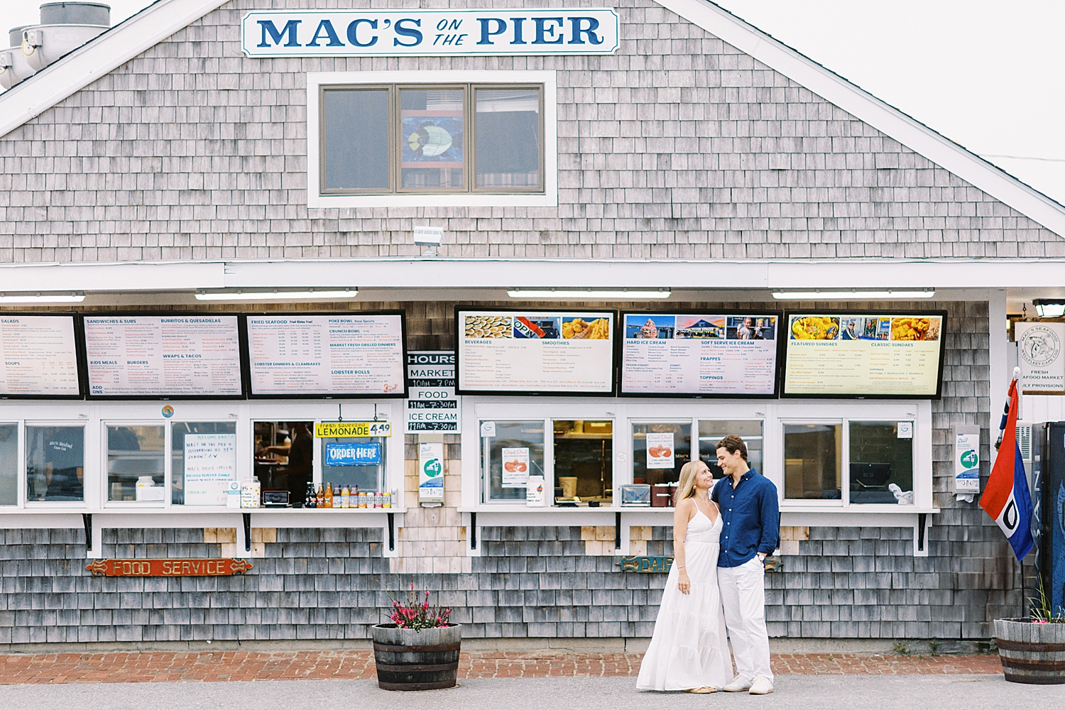 man looks at woman with love on sidewalk for Engagement Session in Wellfleet