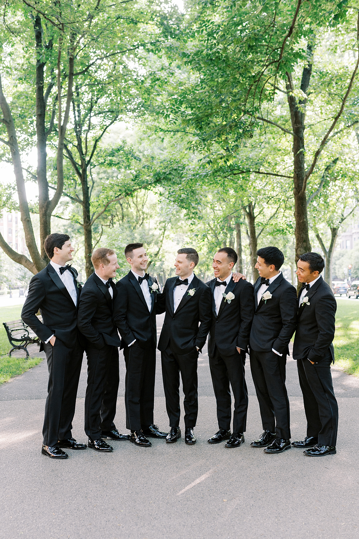 groom and groomsmen laugh together on Comm Ave Mall in Boston by New England Wedding Photographer