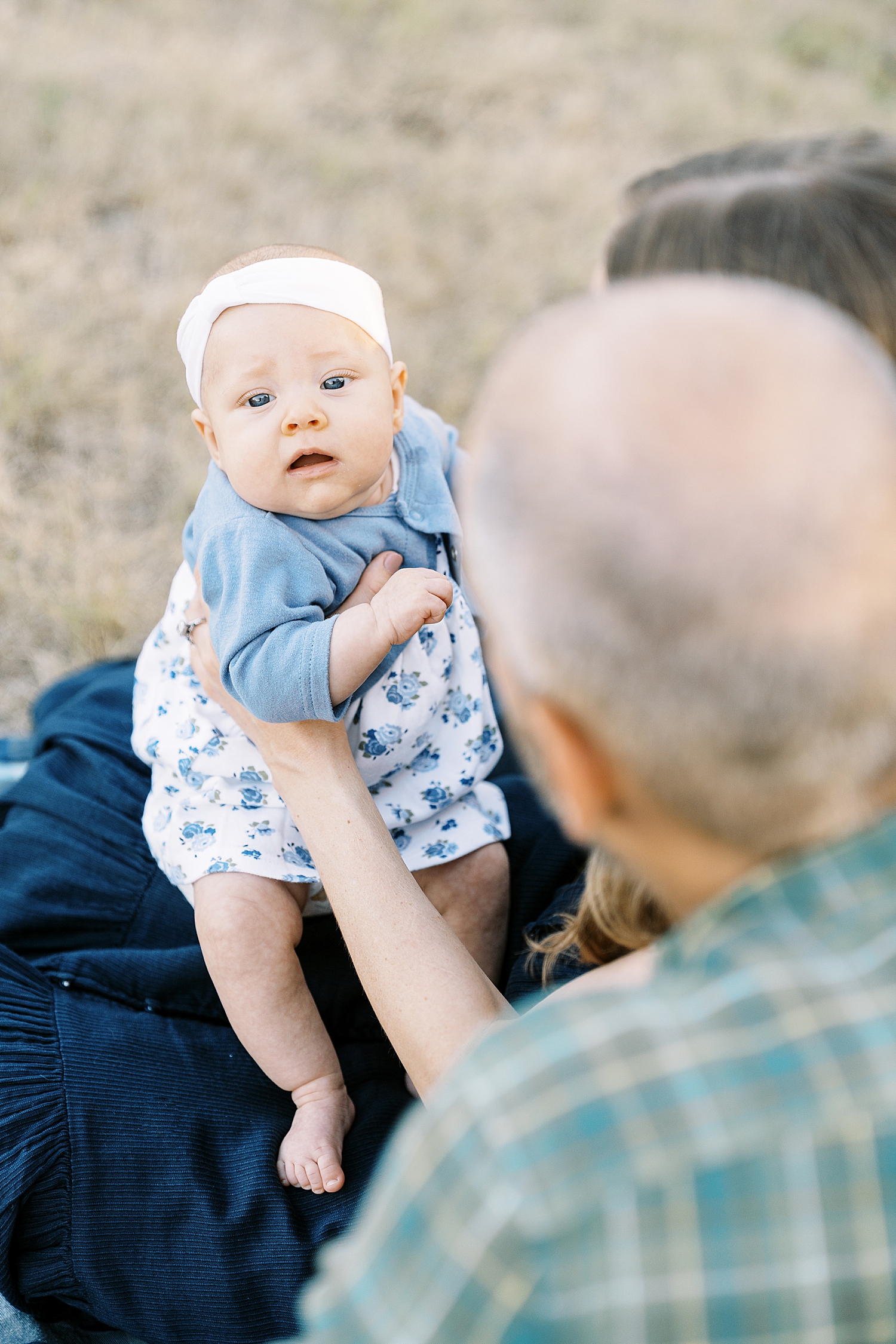 small baby in blue dress held by her mother by Lynne Reznick Photography