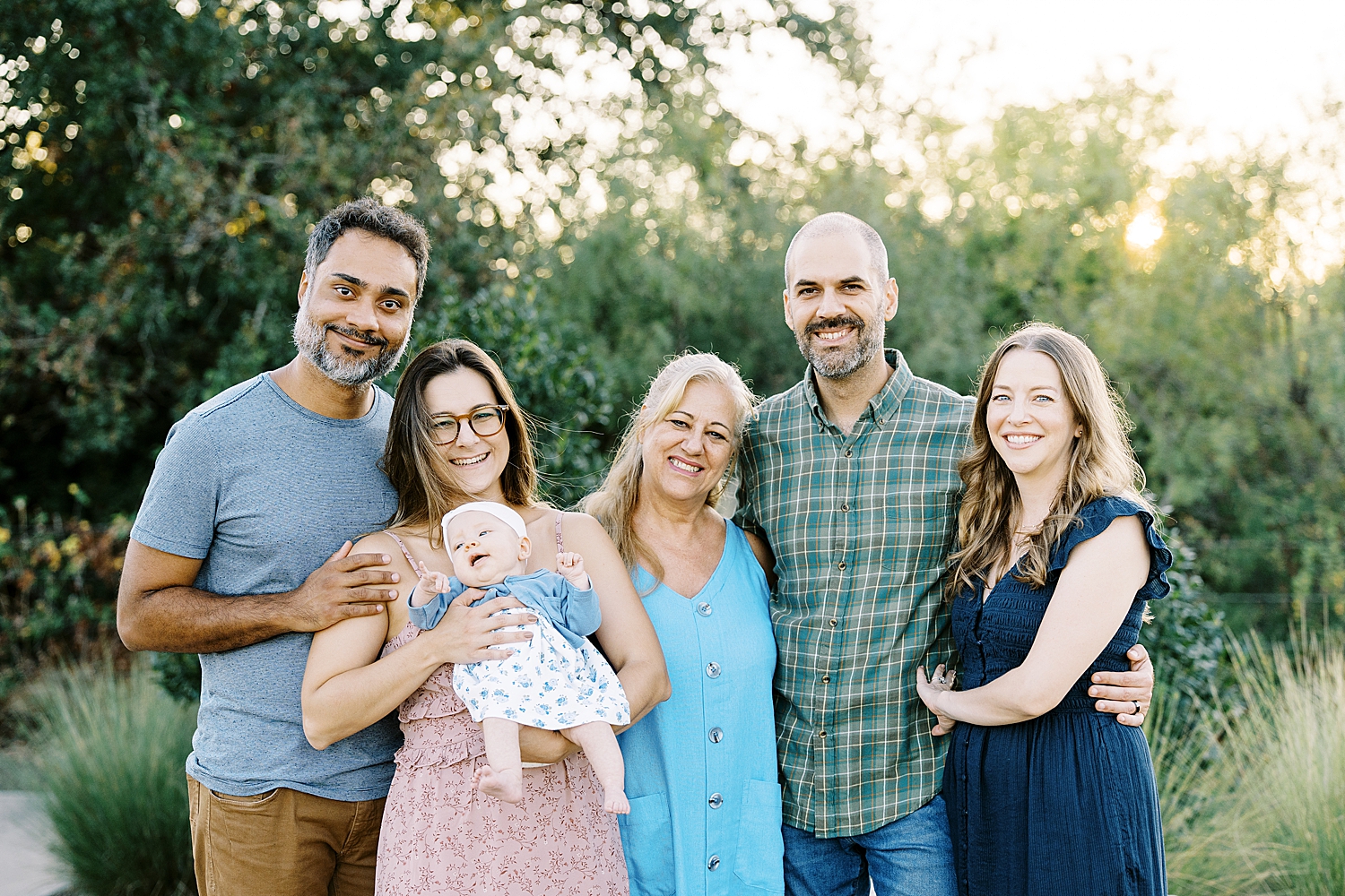 5 adults stand in front of trees holding infant by Lynne Reznick Photography