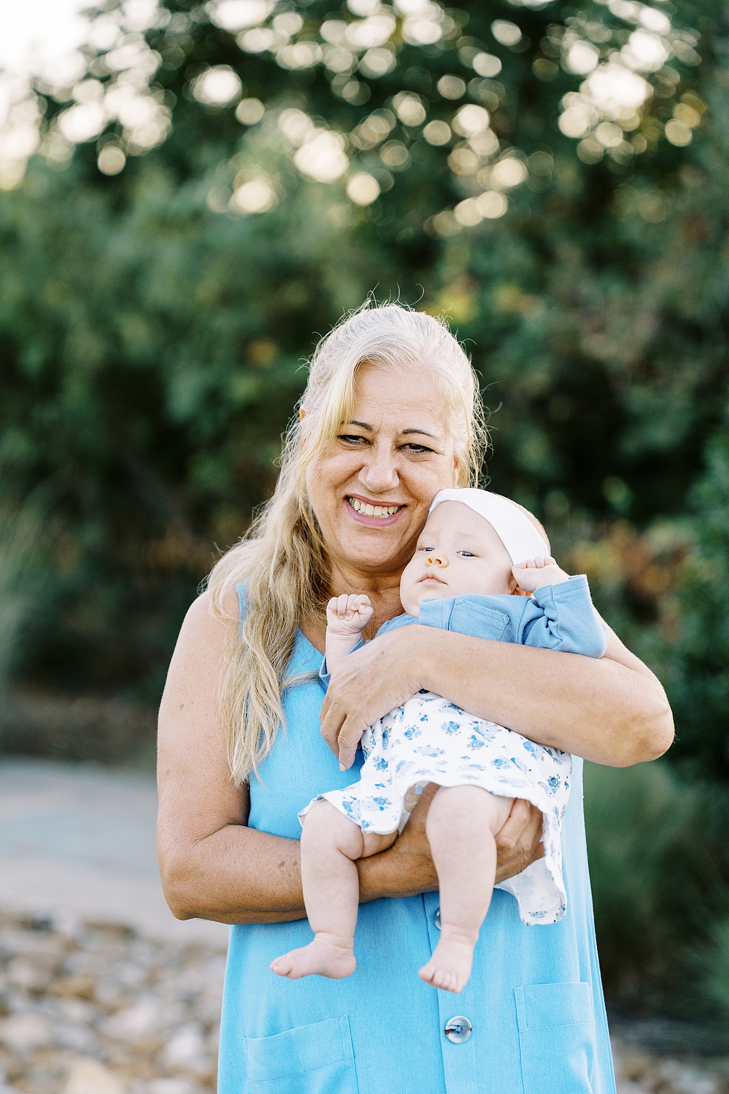grandmother in a blue dress holds up baby by Austin photographer
